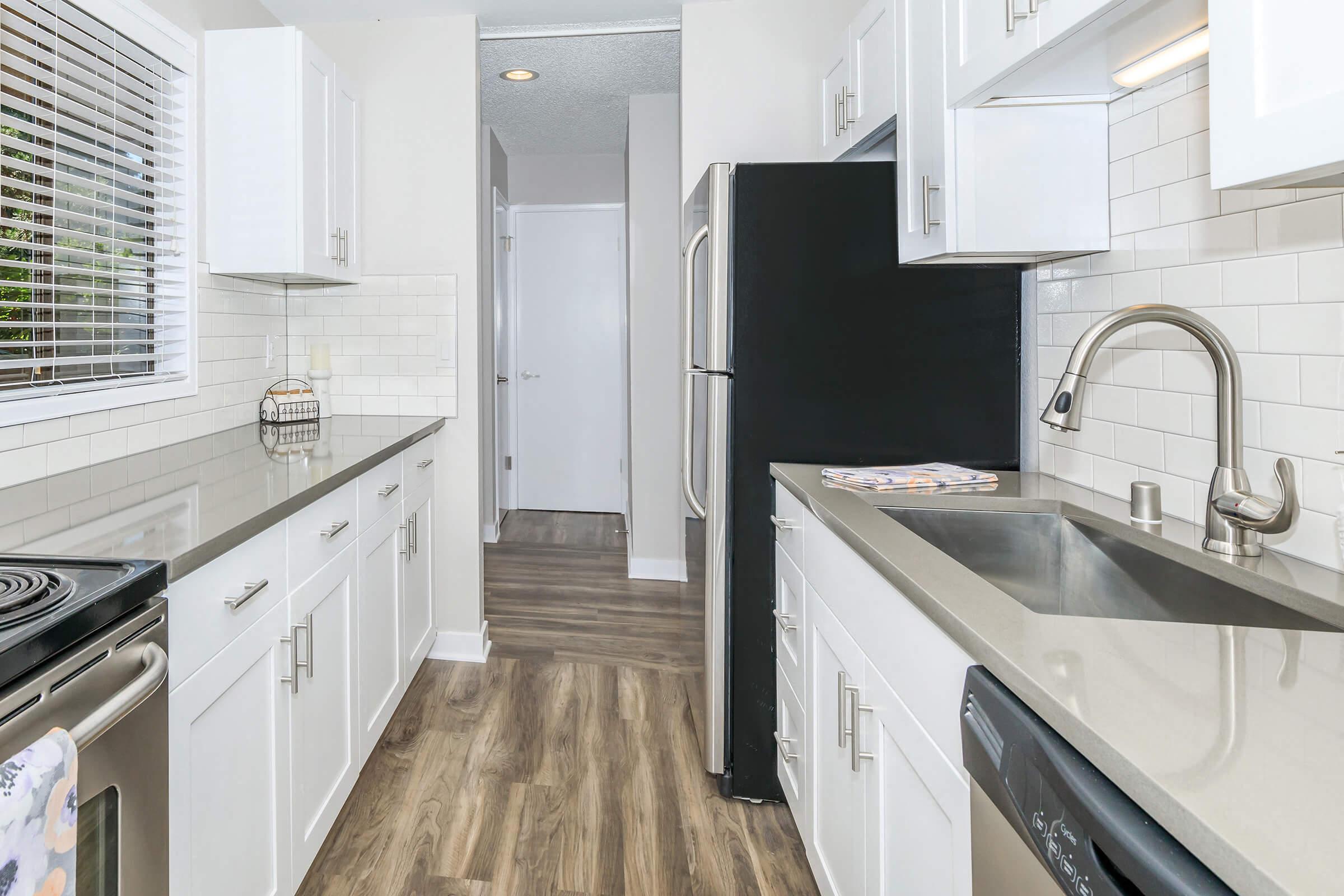 a kitchen with white cabinets and a black refrigerator