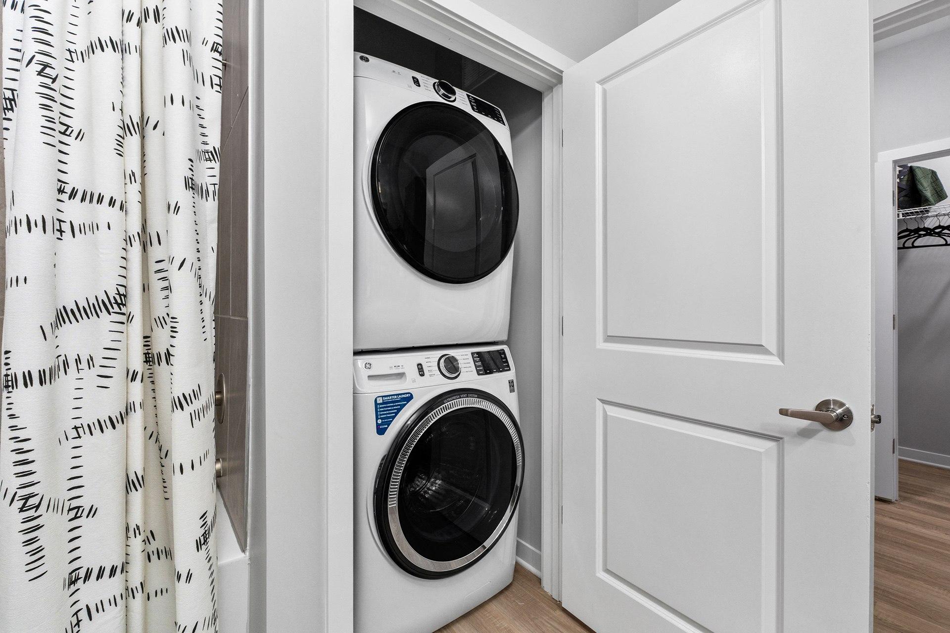A white washing machine is in a small white closet.