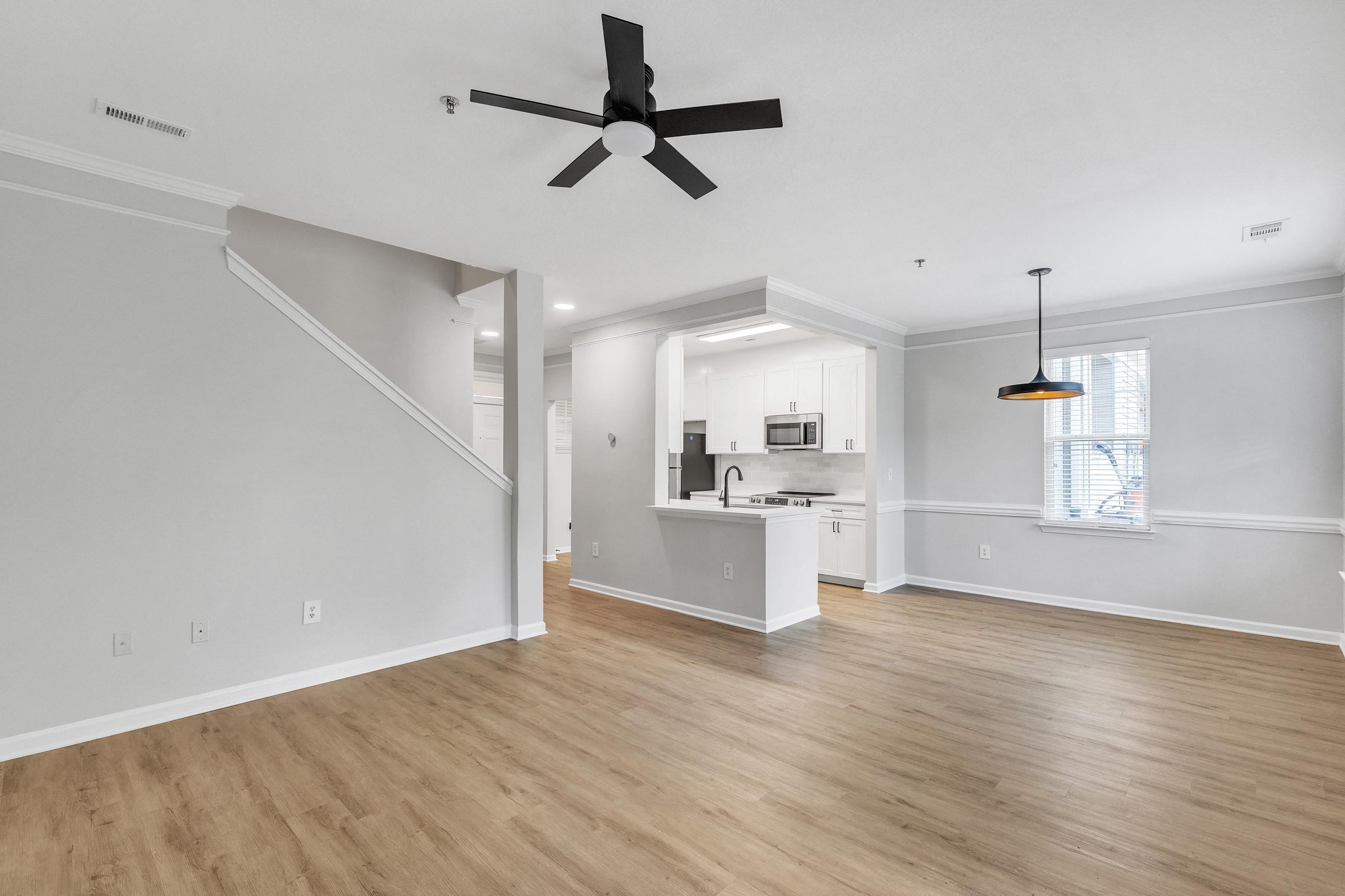 A spacious kitchen and living room with a ceiling fan and hardwood floors.