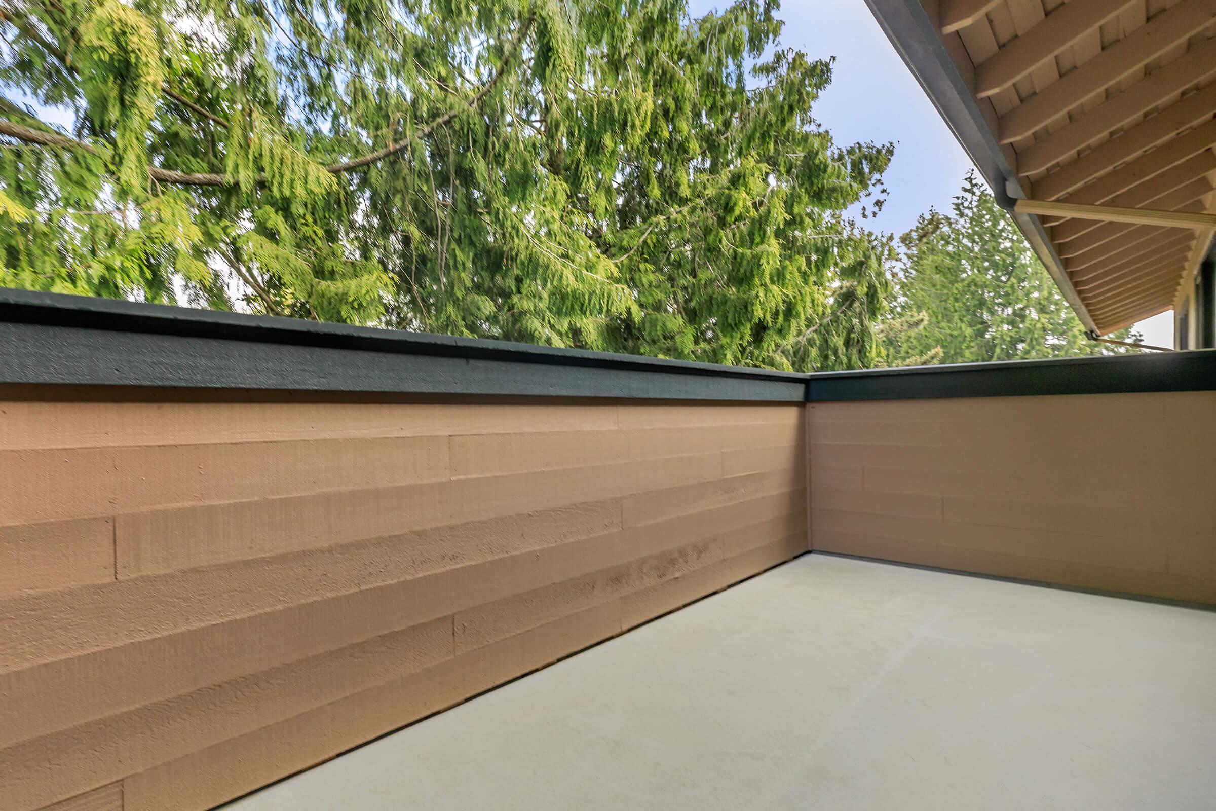 a patio with a wall and a tree in the background