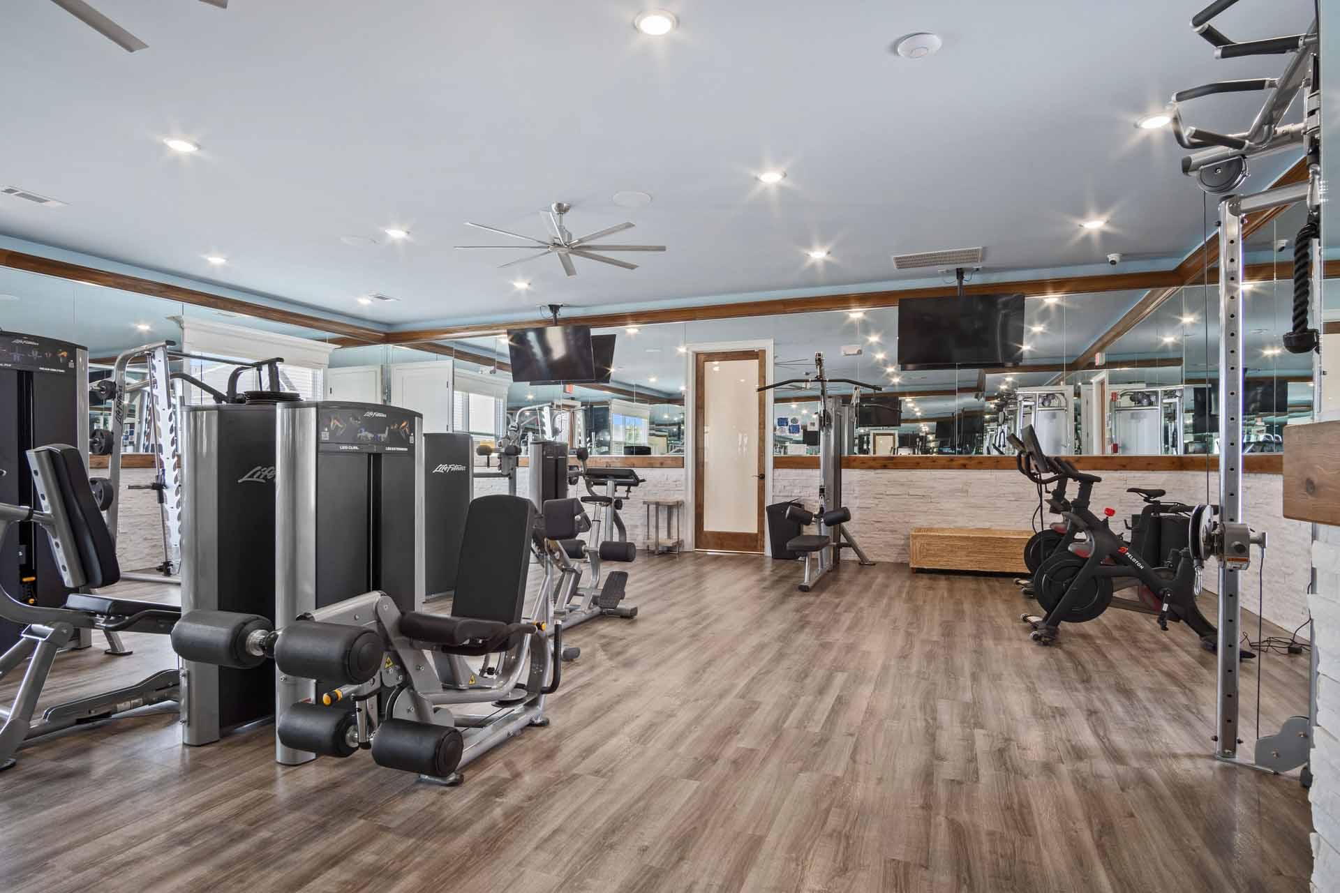 A gym with a variety of equipment including treadmills, weights, and a bench press.