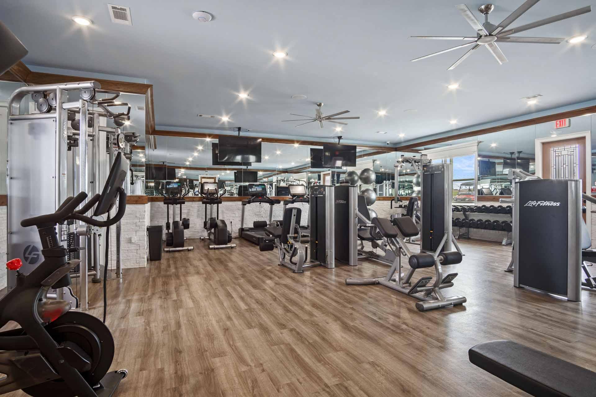 A gym with a variety of equipment including treadmills, weights, and exercise machines.