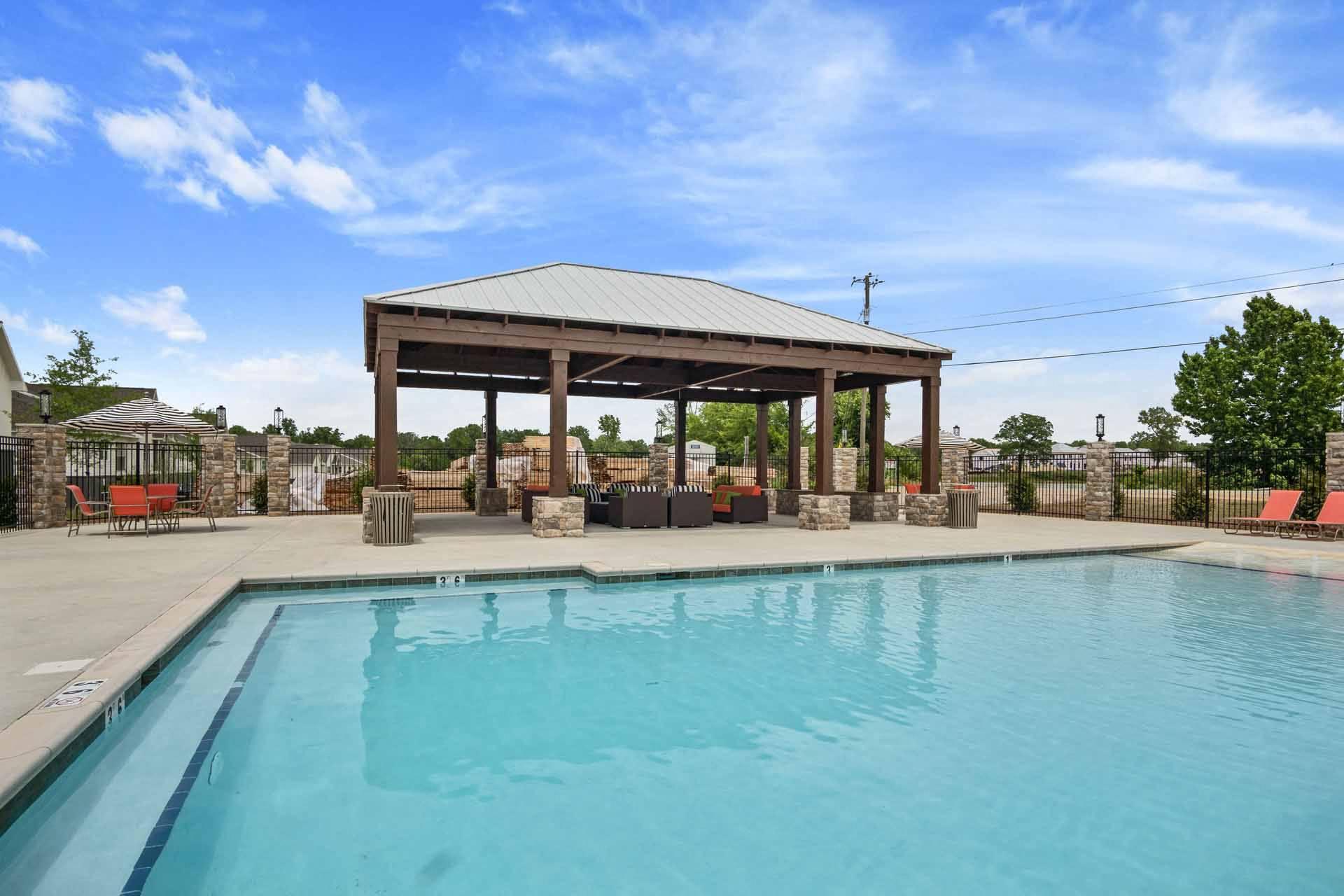A pool with a pavilion in the background.