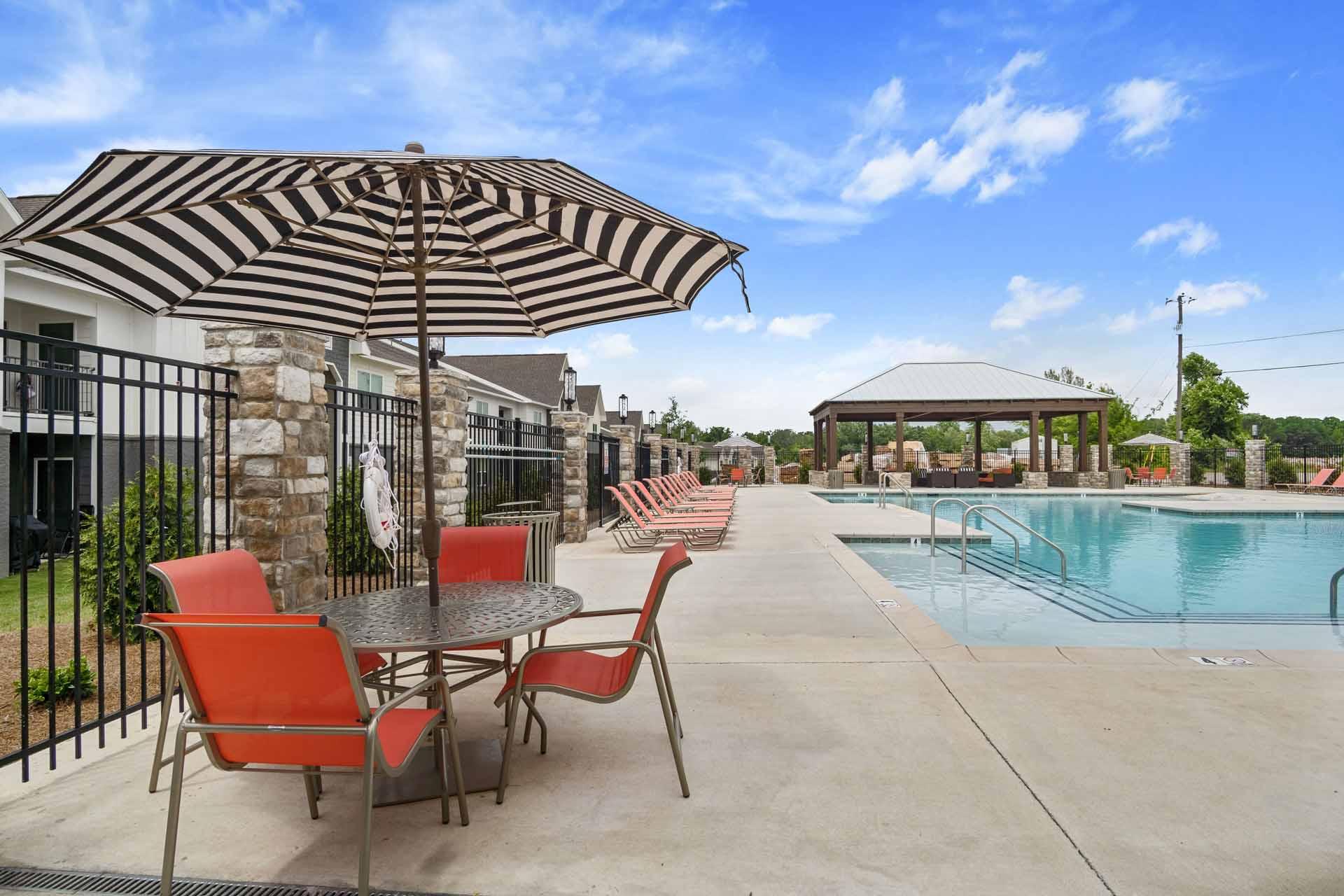 A patio with a table and chairs is set up next to a pool.