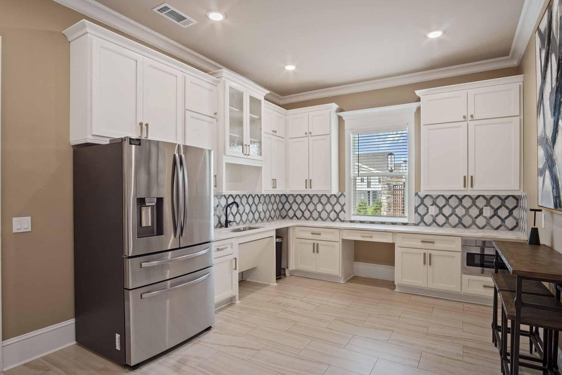 A kitchen with a black refrigerator and white cabinets.