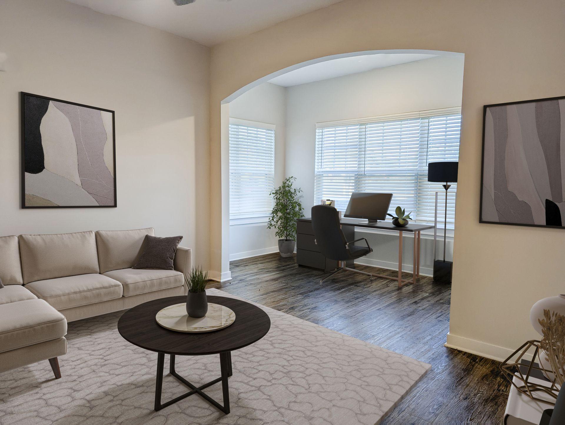 A living room with a white couch, a black chair, and a small table with a plant on it.