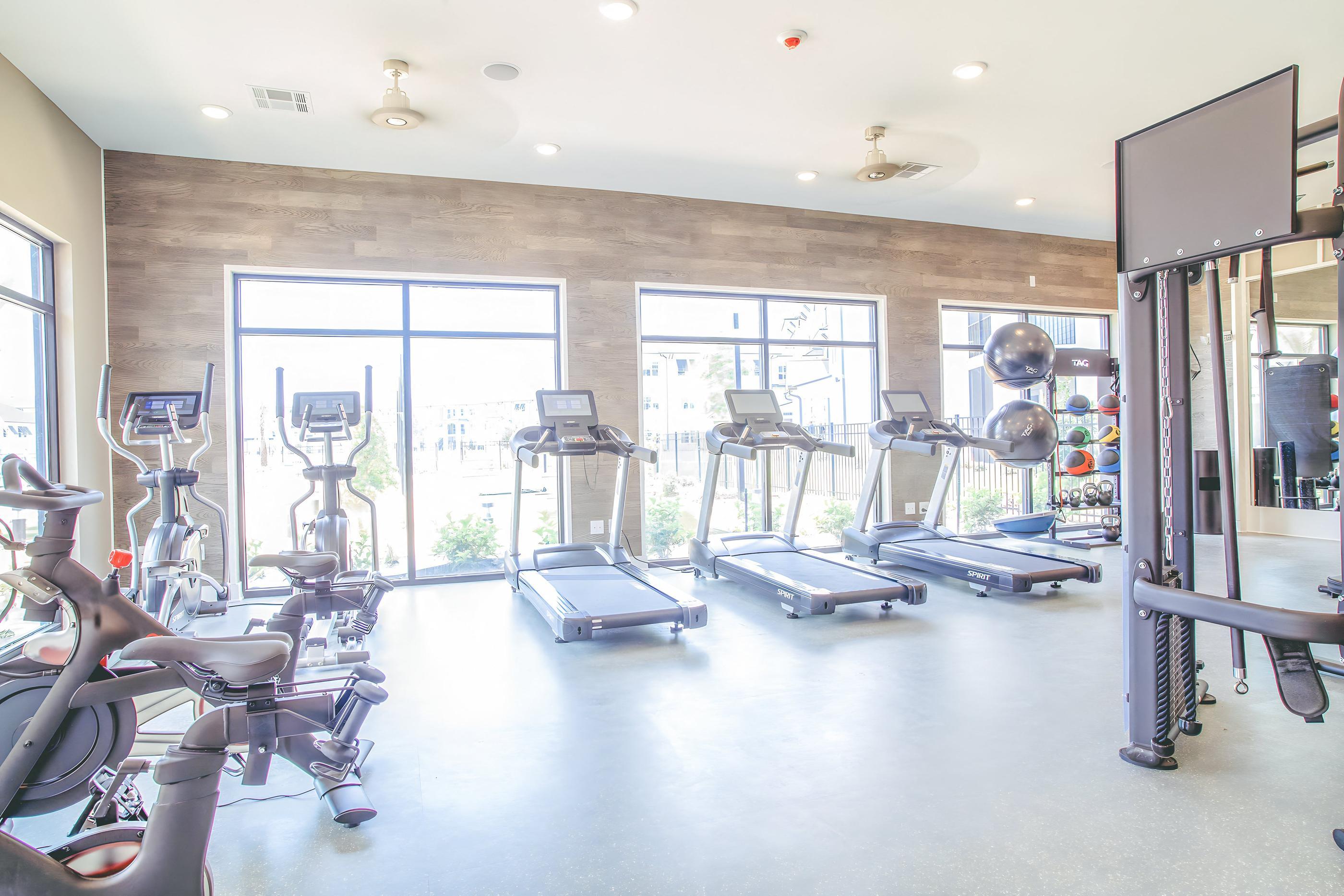 a gym with cardio equipment and windows