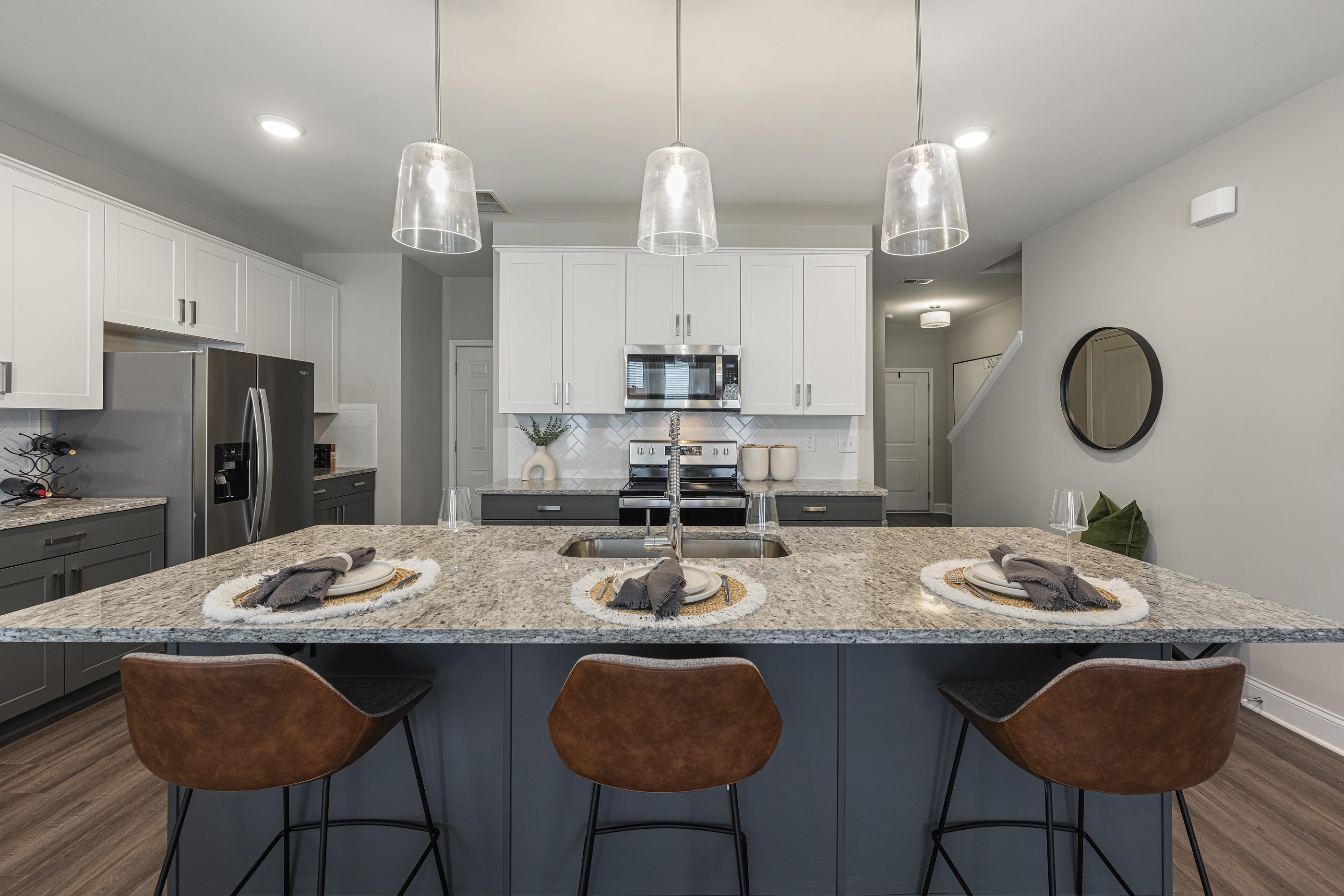 A modern kitchen with a granite countertop and bar stools.