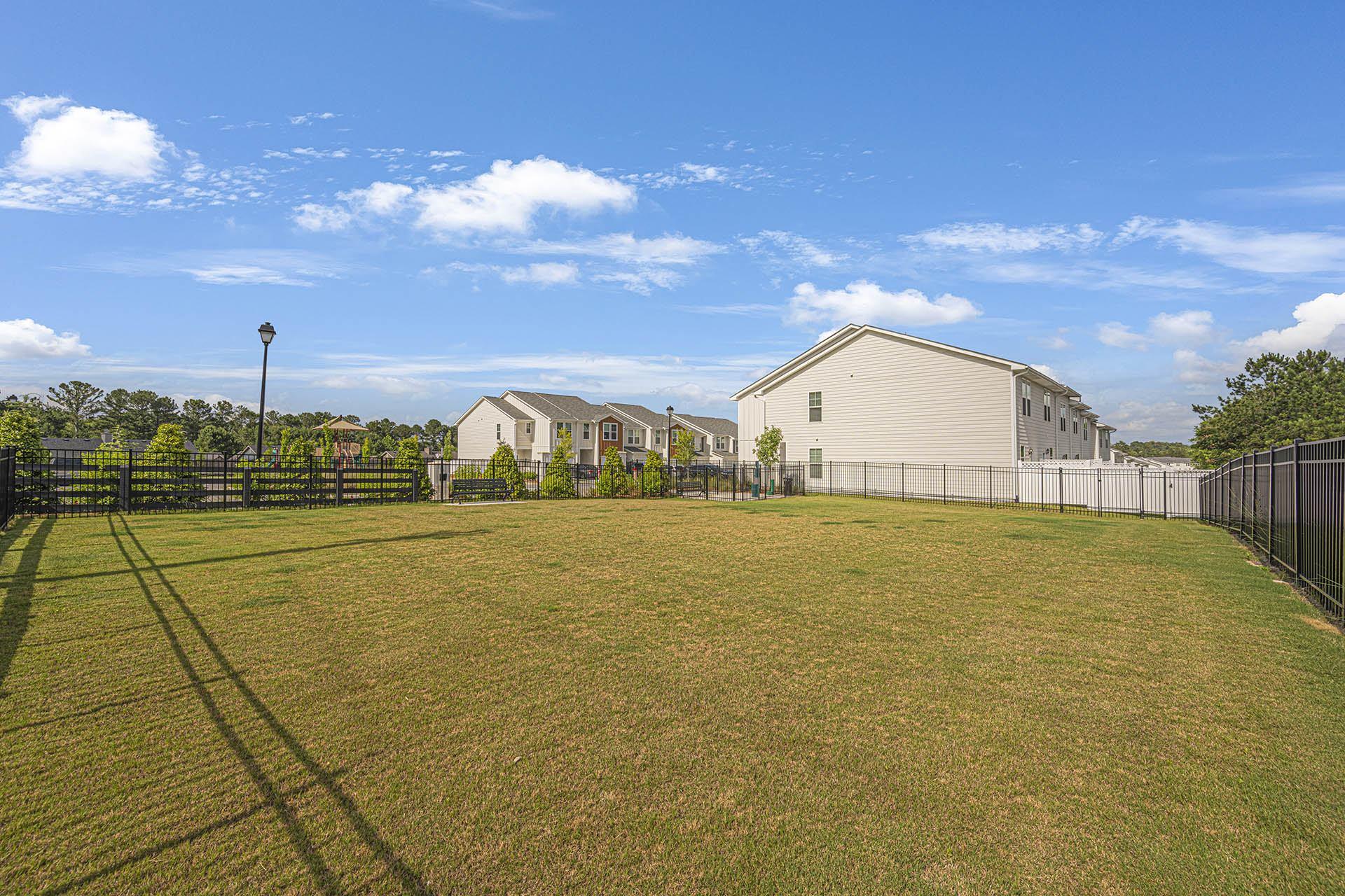 A grassy field with a fence and a building in the background.
