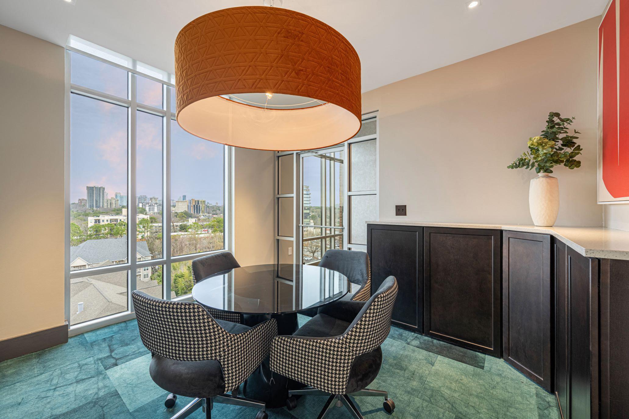 a dining area with a glass table and chairs and a large window