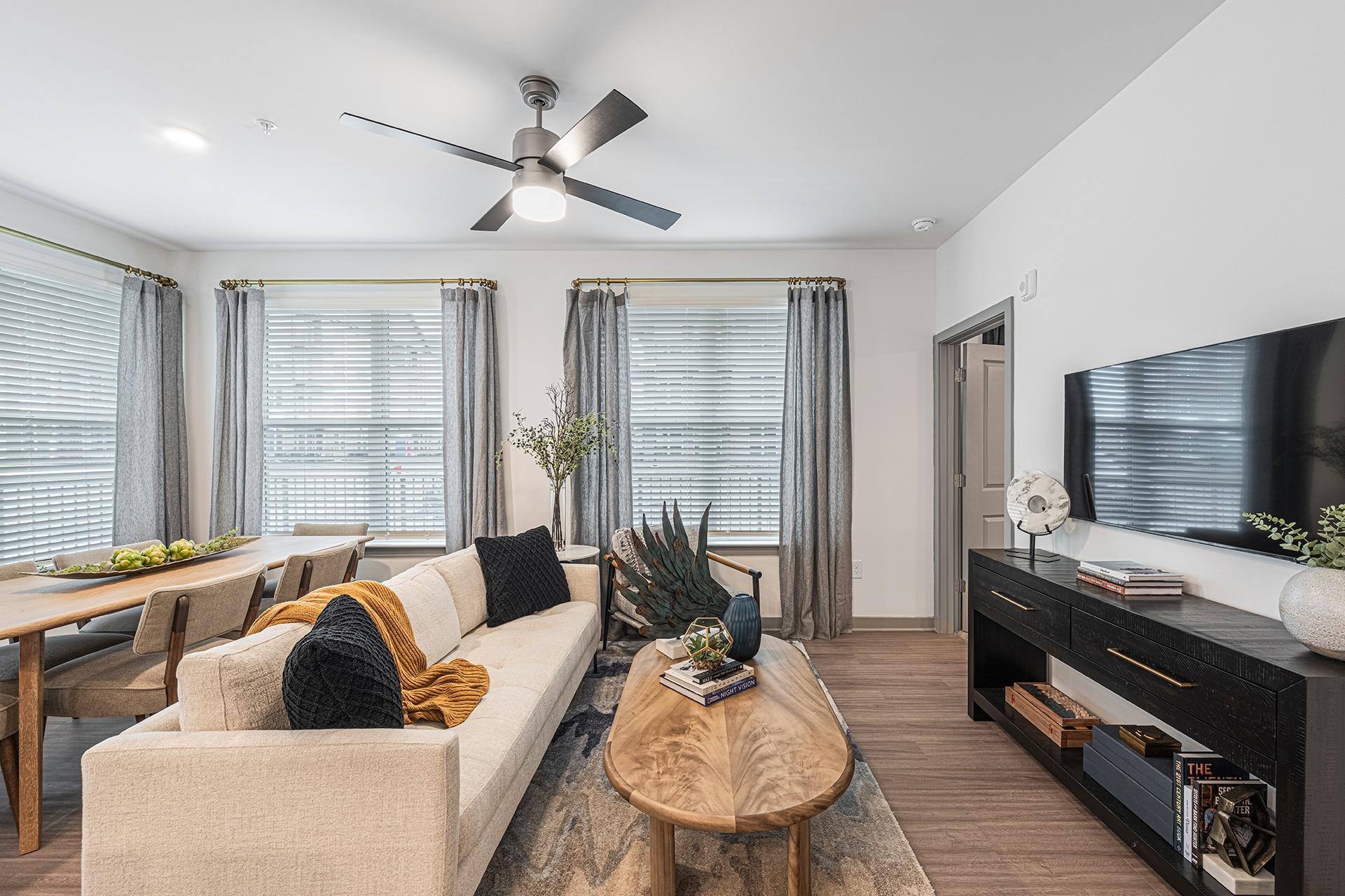 A living room with a beige couch, a wooden coffee table, and a ceiling fan.