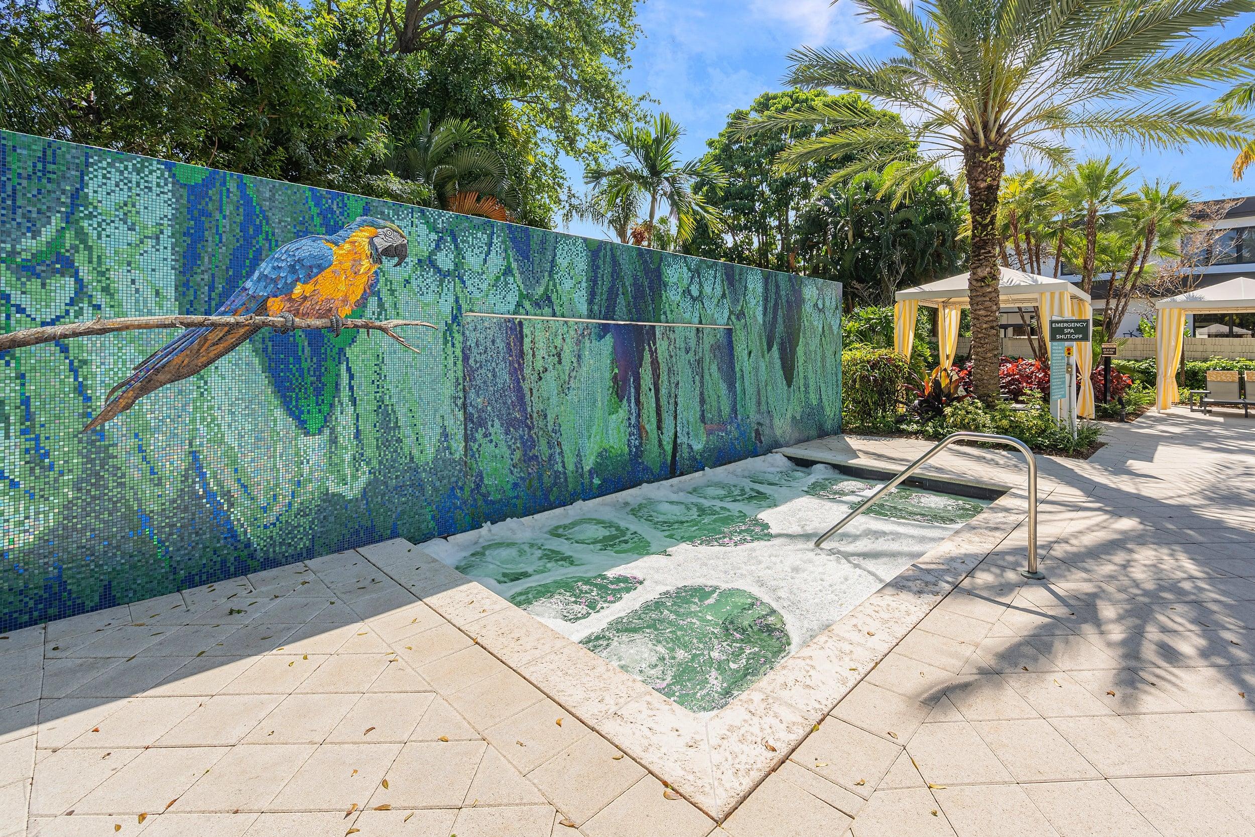 a colorful mural of a parrot on a wall next to a fountain