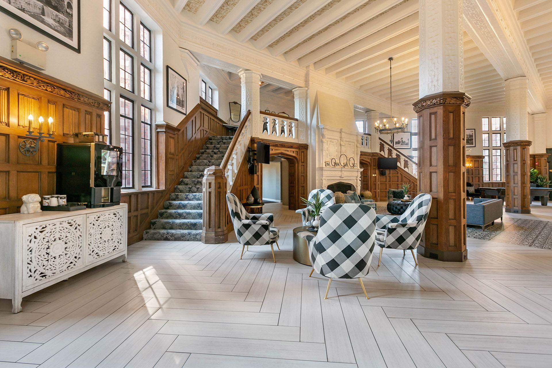A large, well-lit room with a staircase and a checkered chair set.