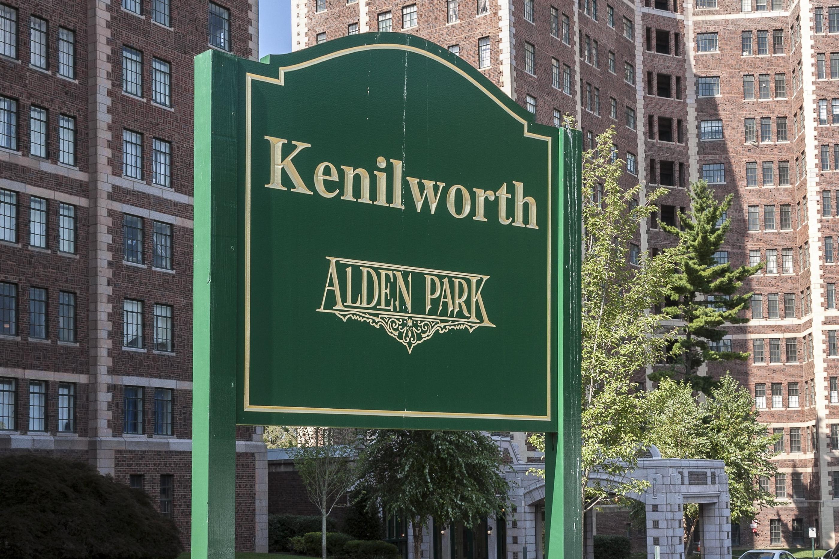 A green sign that says Kenilworth Alden Park stands in front of a building.