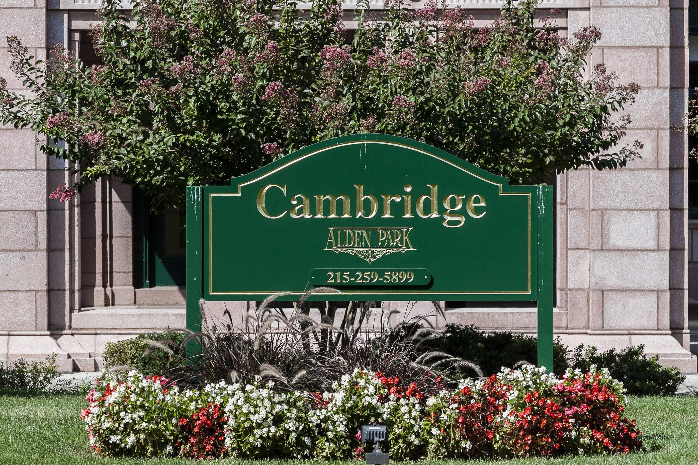 A green sign that says Cambridge Aiden Park in front of a building.