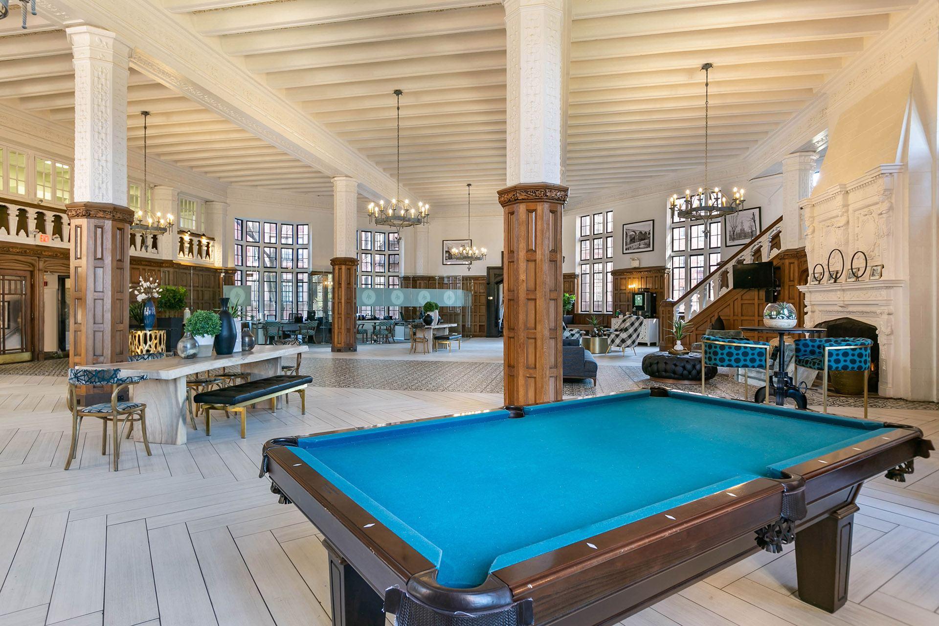 A pool table is in the middle of a room with a lot of furniture.