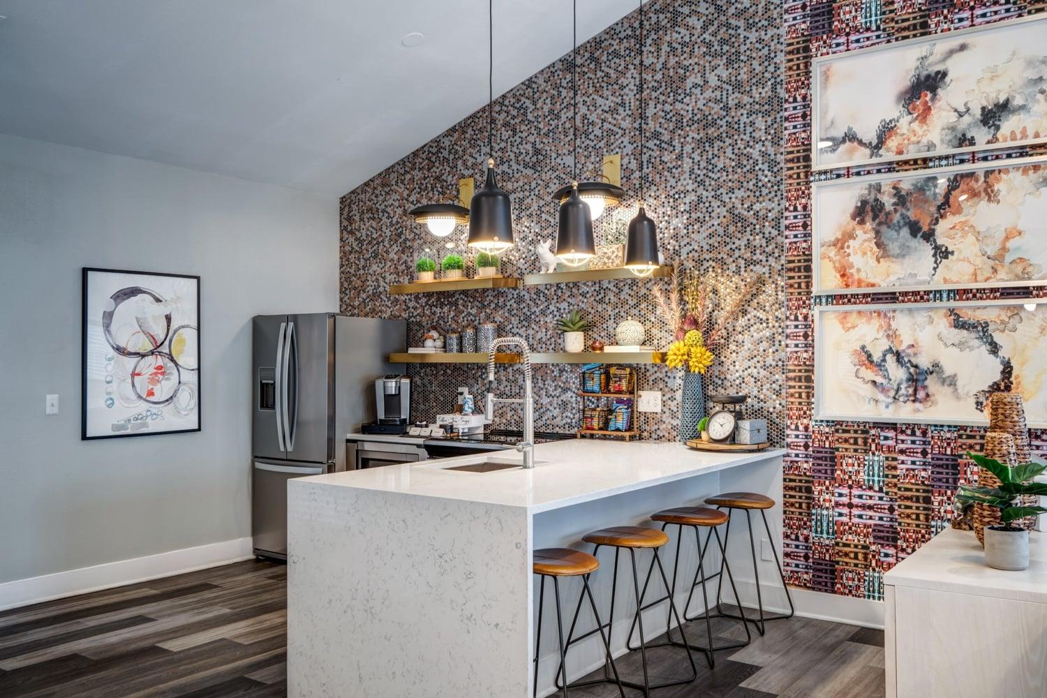 A kitchen with a white counter and a wall covered in a mosaic of different paintings.