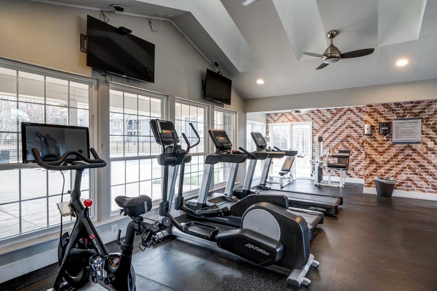 A gym with treadmills, exercise bikes, and a television.