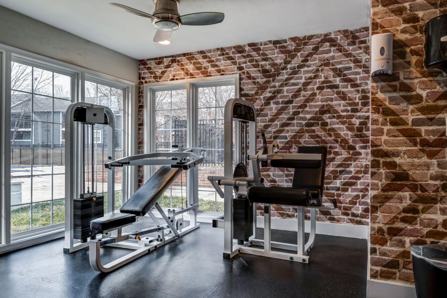 A gym room with a brick wall and a rowing machine.