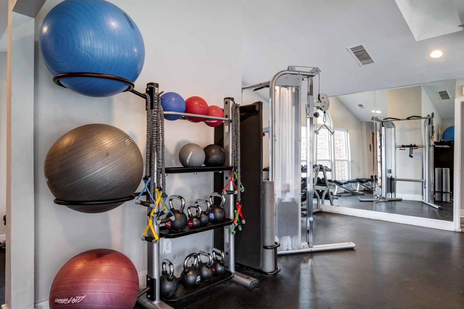 A gym with a variety of equipment and exercise balls.