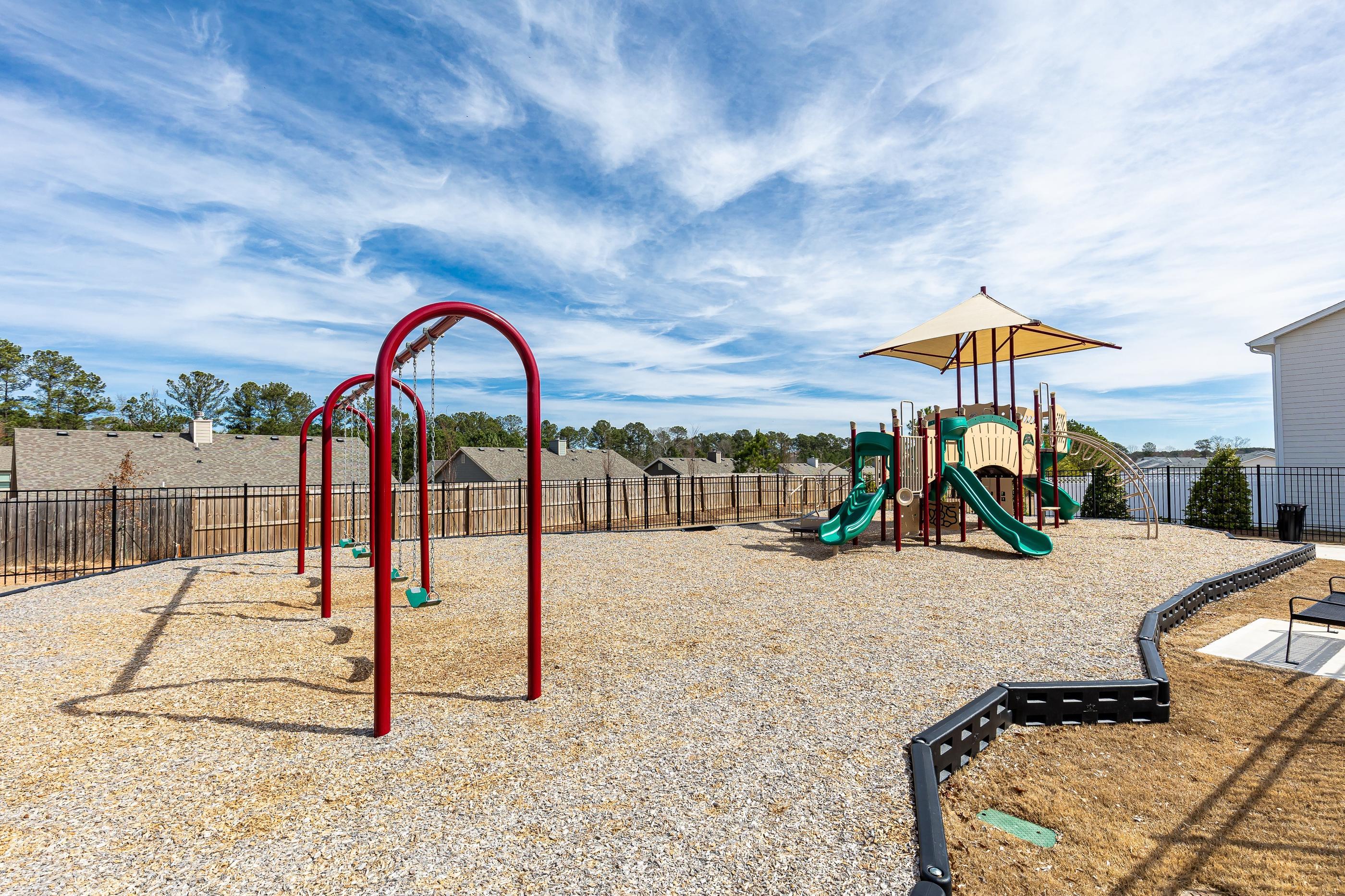 A playground with a red swing set and a green slide.