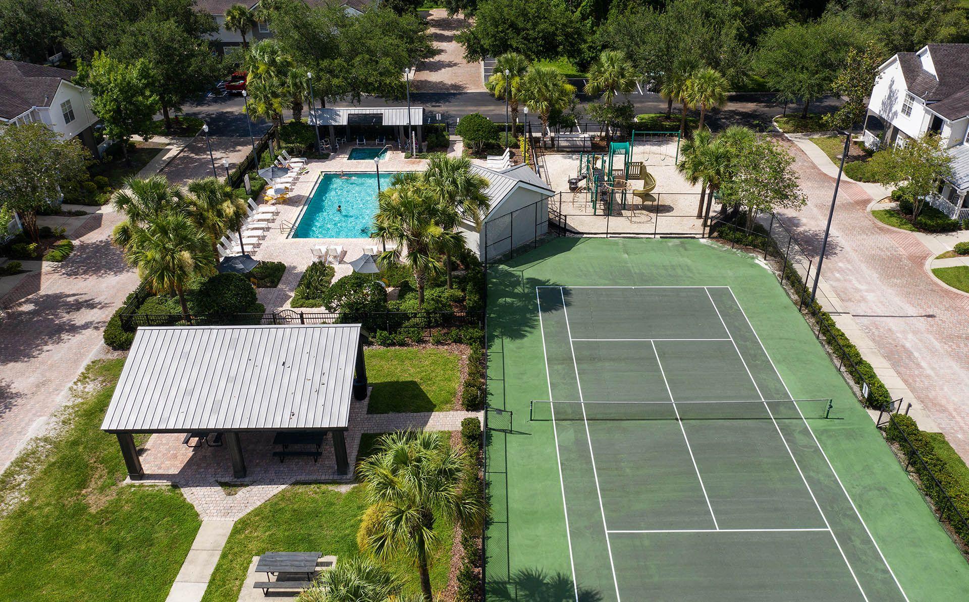 an aerial view of a tennis court and a pool in the backyard of a house