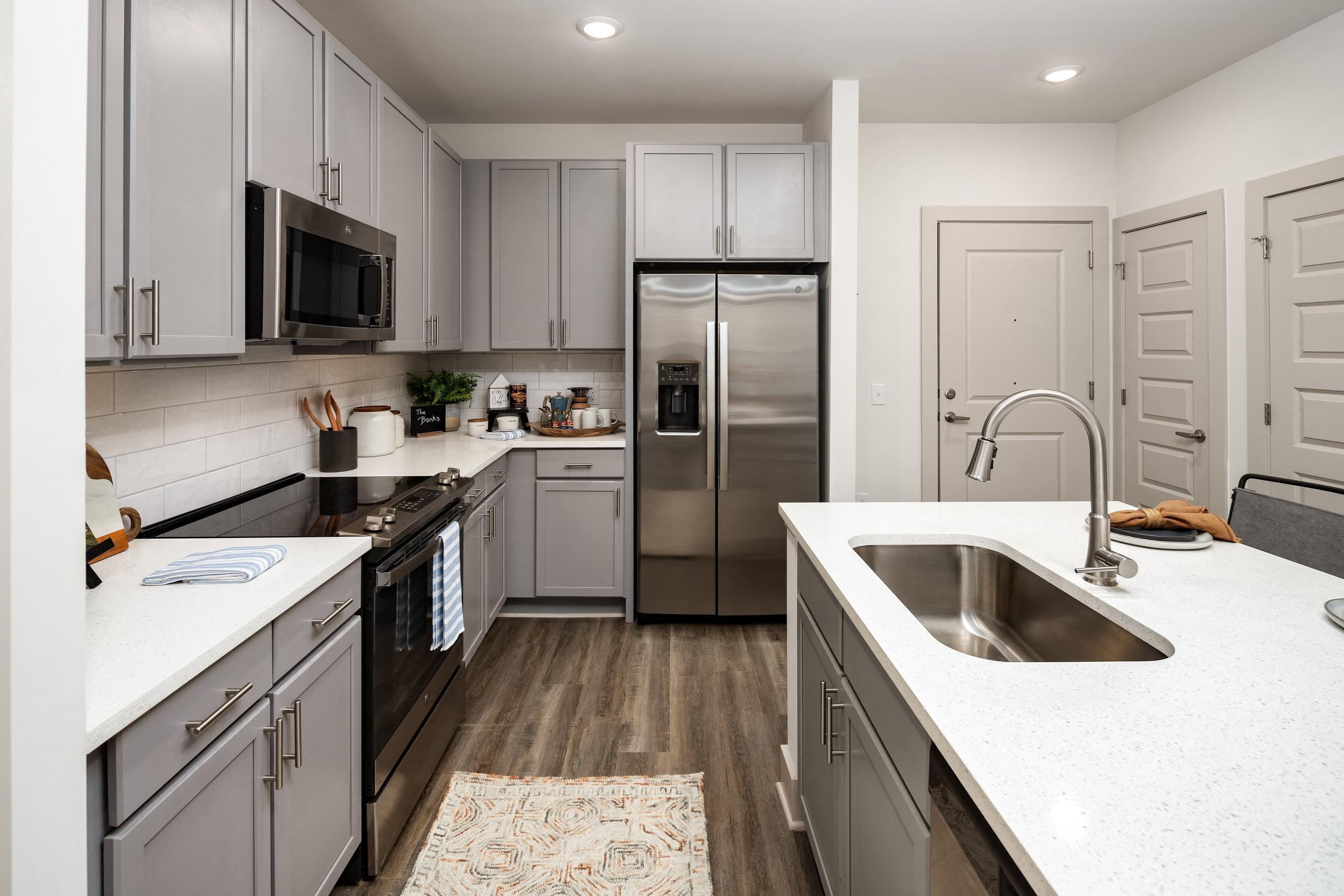 a large kitchen with white counter tops and stainless steel appliances