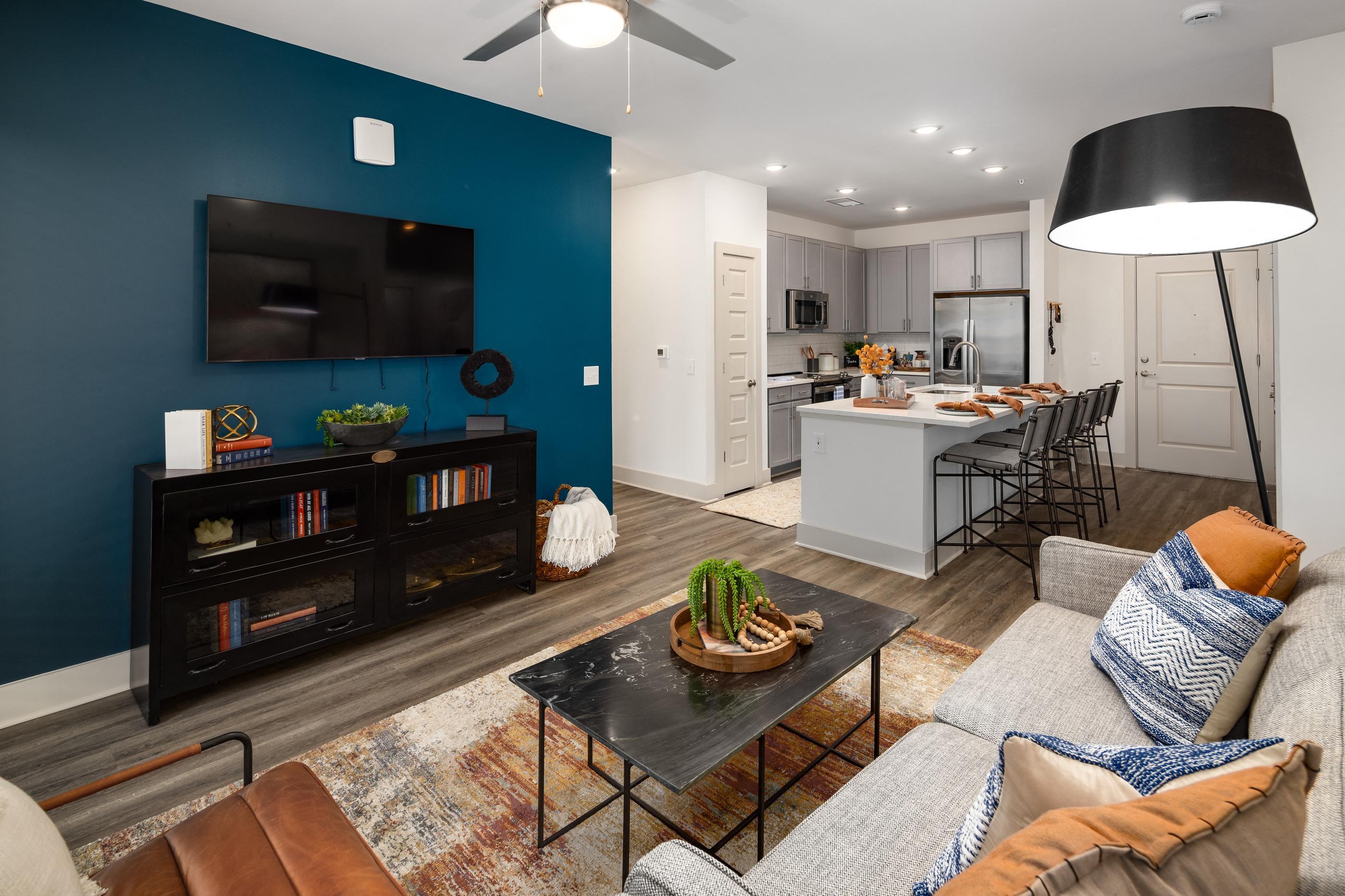 a living room with a blue accent wall and a kitchen with a table and chairs