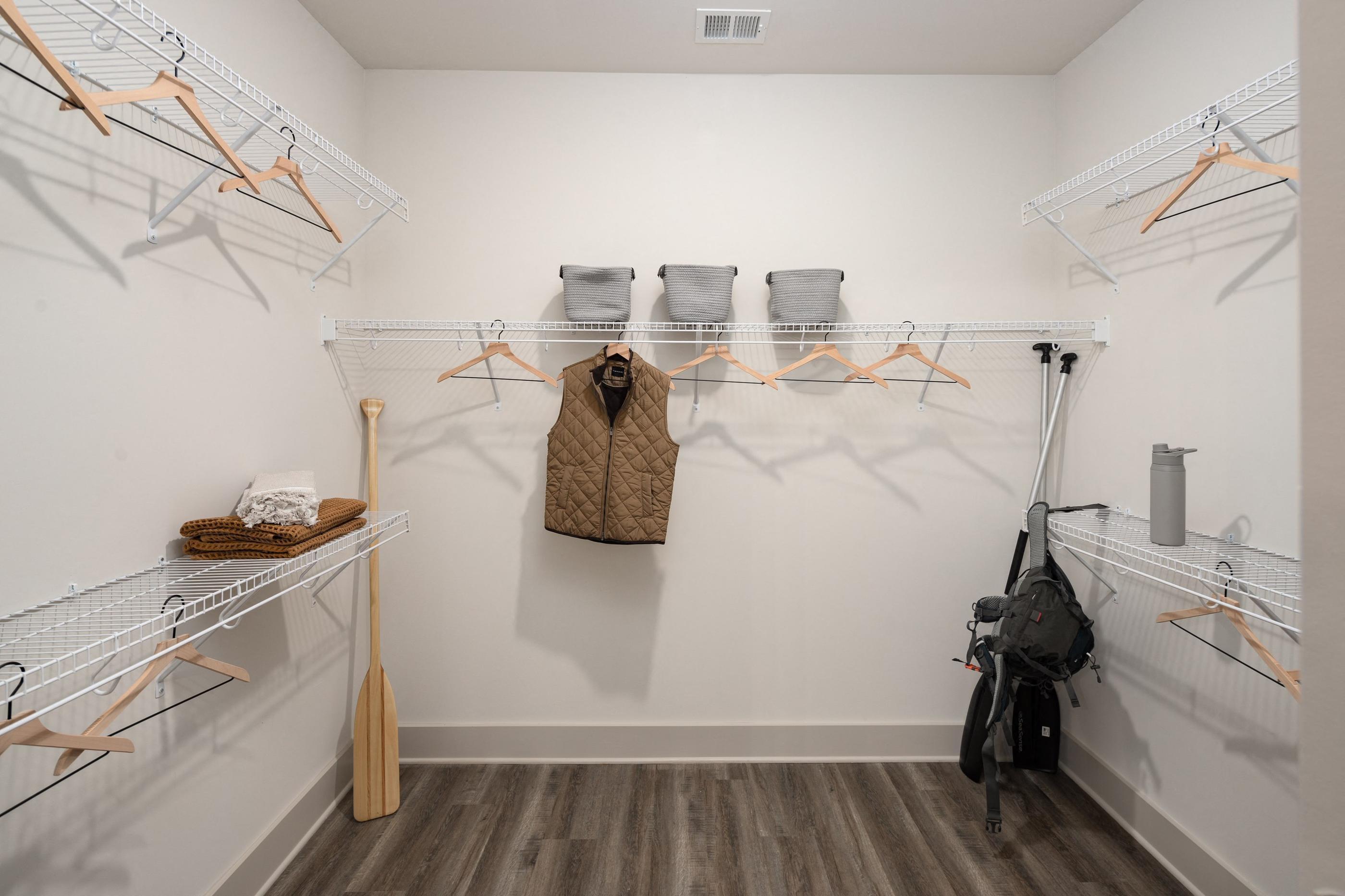 a walk in closet with racks and a bag hanging on the wall