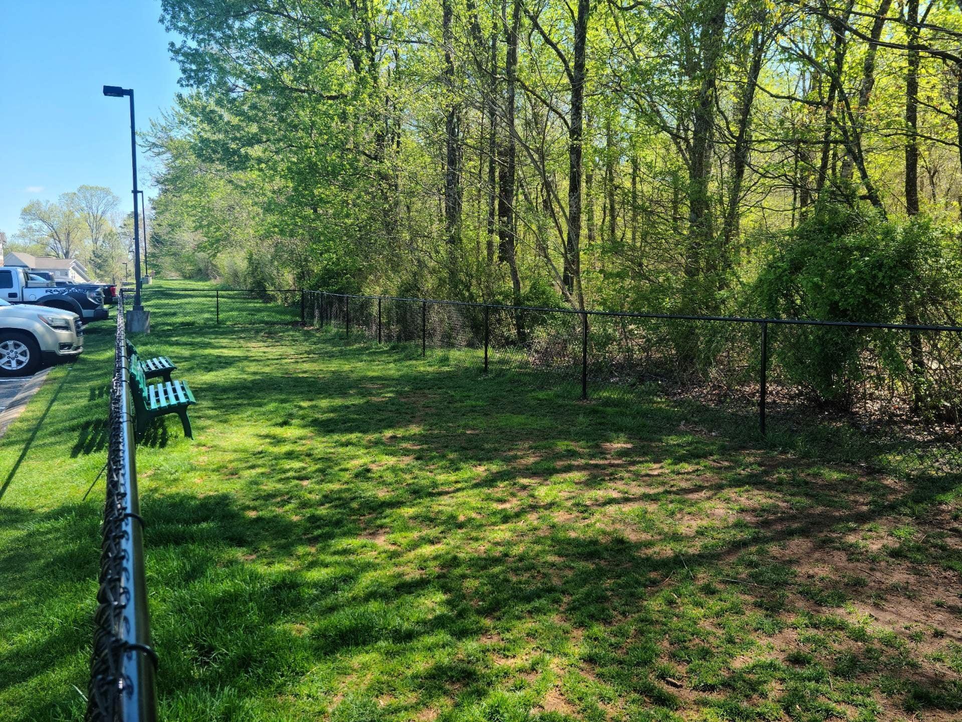 A park with a fence and green grass.
