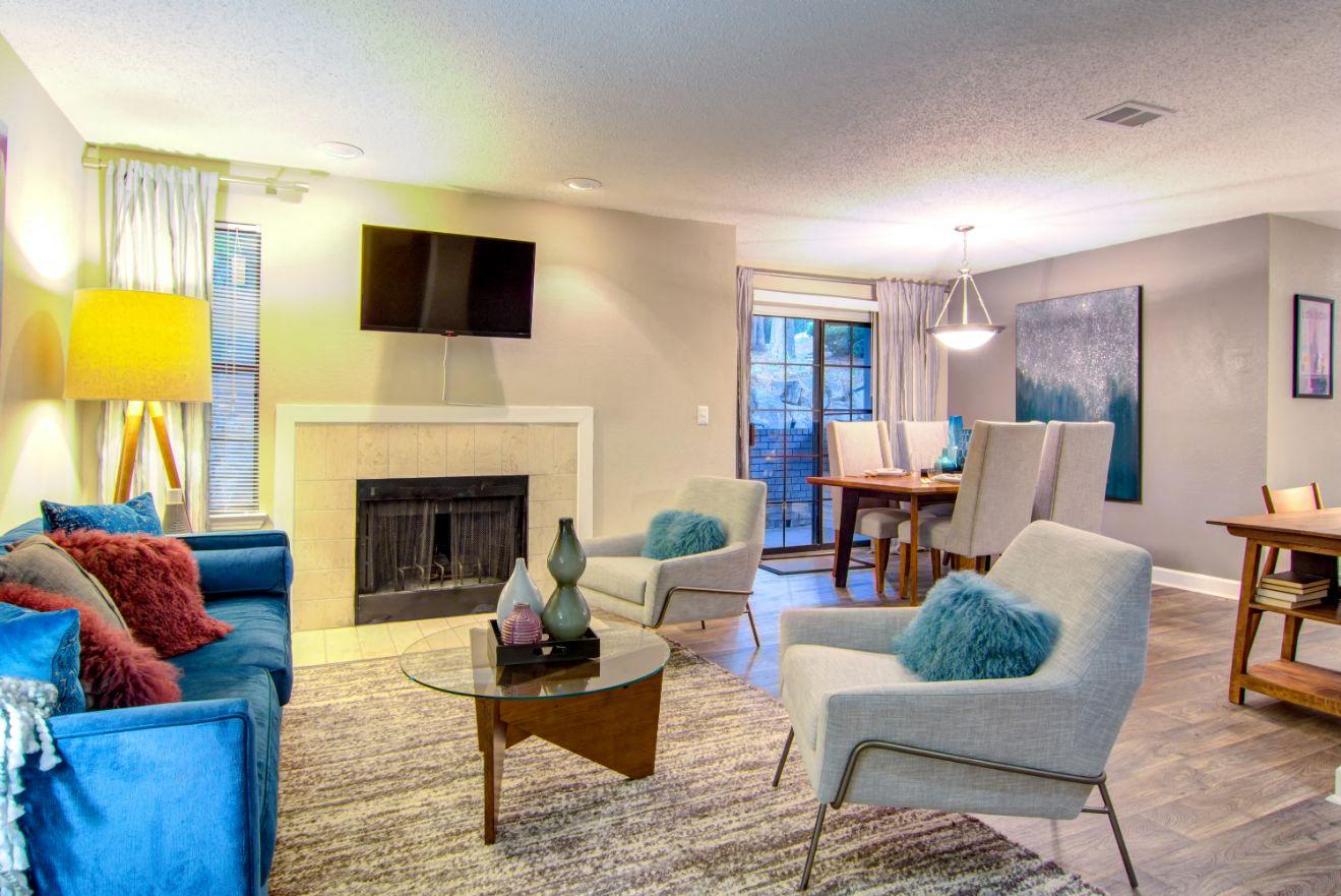 a living room with a fireplace and a dining room in the background