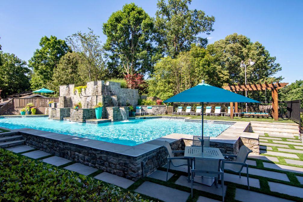 a resort style pool with a waterfall and lounge chairs with umbrellas