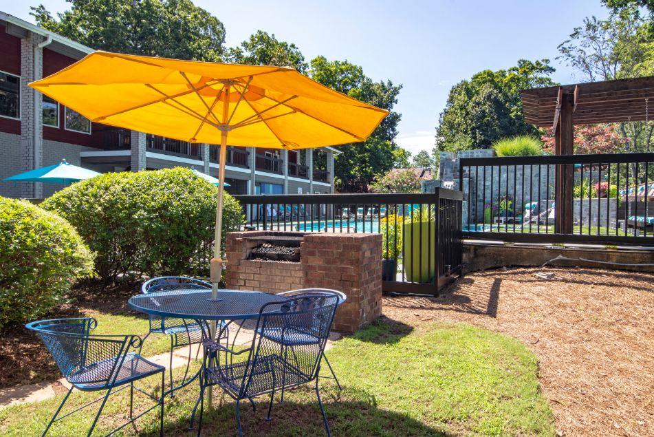 a patio with a table and chairs and a yellow umbrella