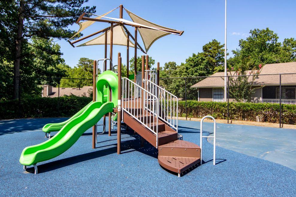 a playground with a green slide and a brown wooden platform