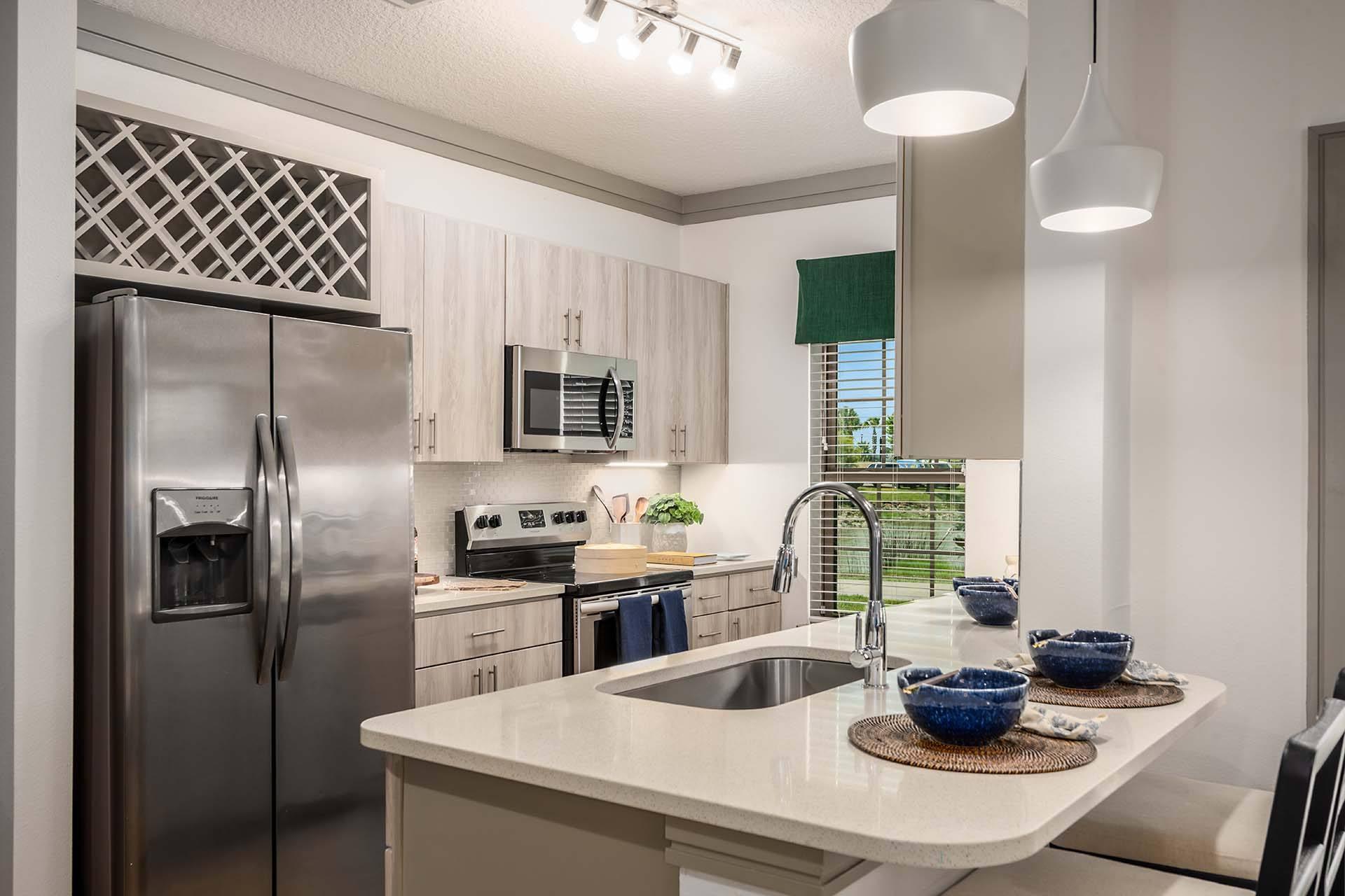 A modern kitchen with a stainless steel refrigerator and a white countertop.