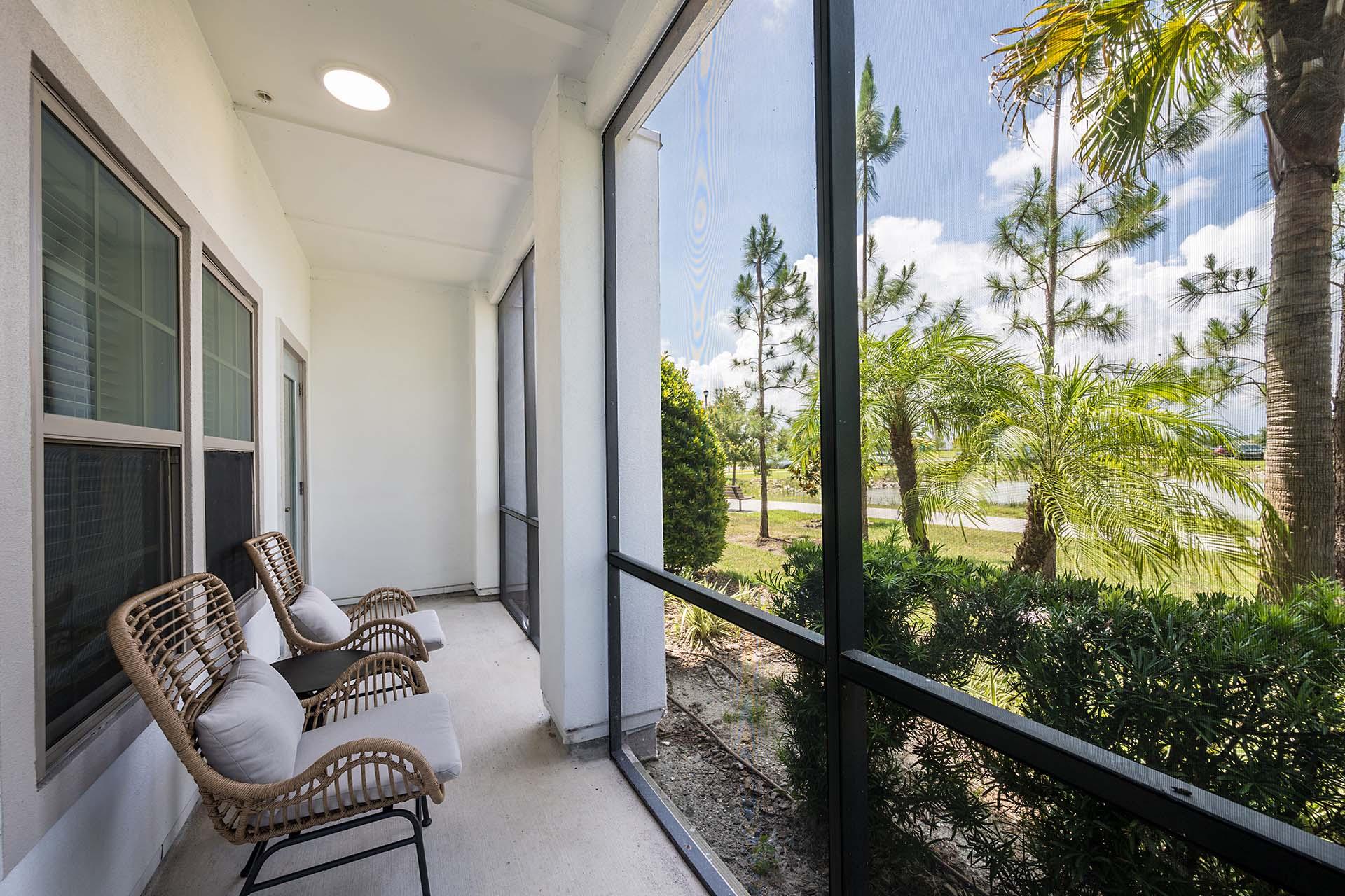 A patio with chairs and a view of a garden.