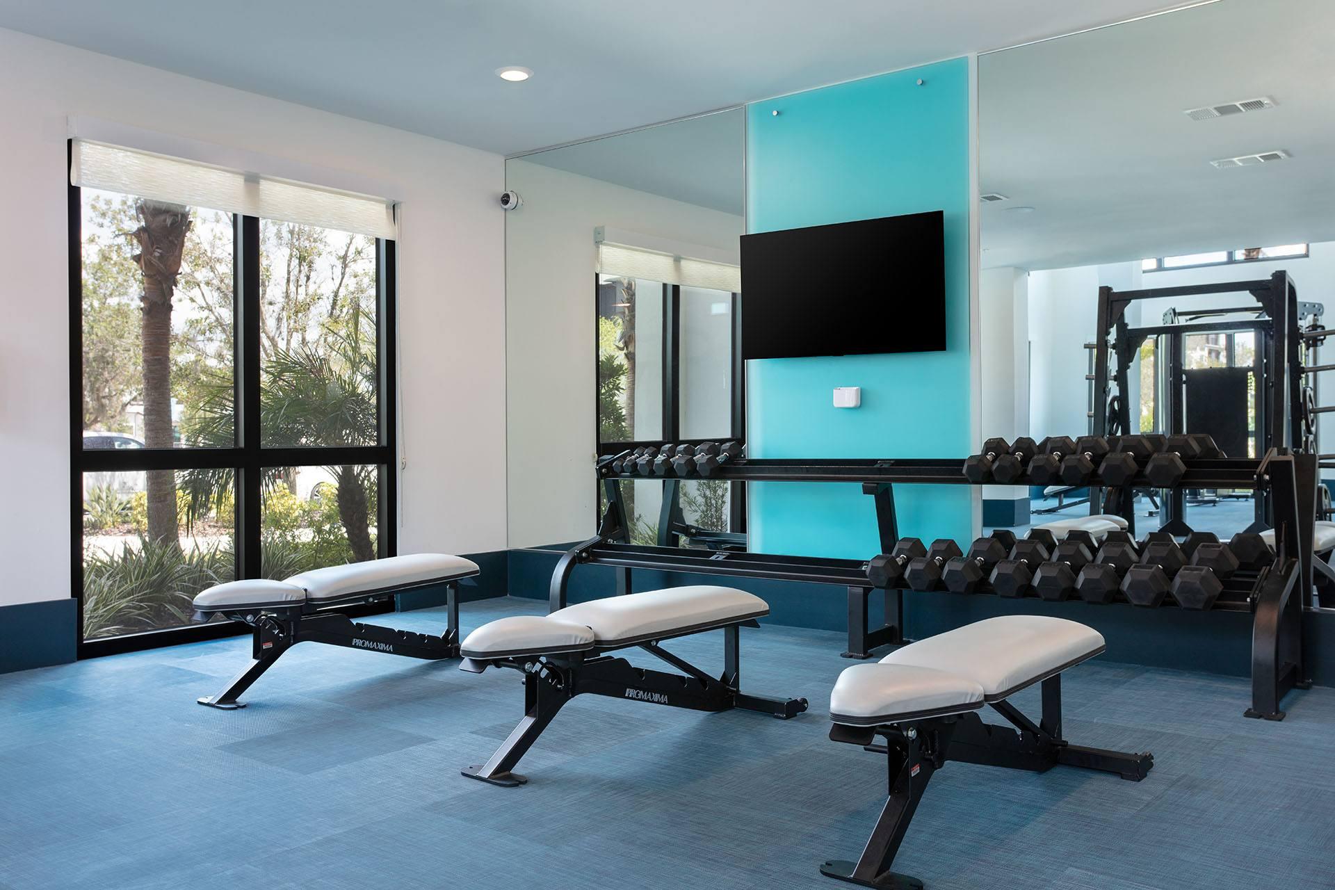 A gym with a row of benches and a television.