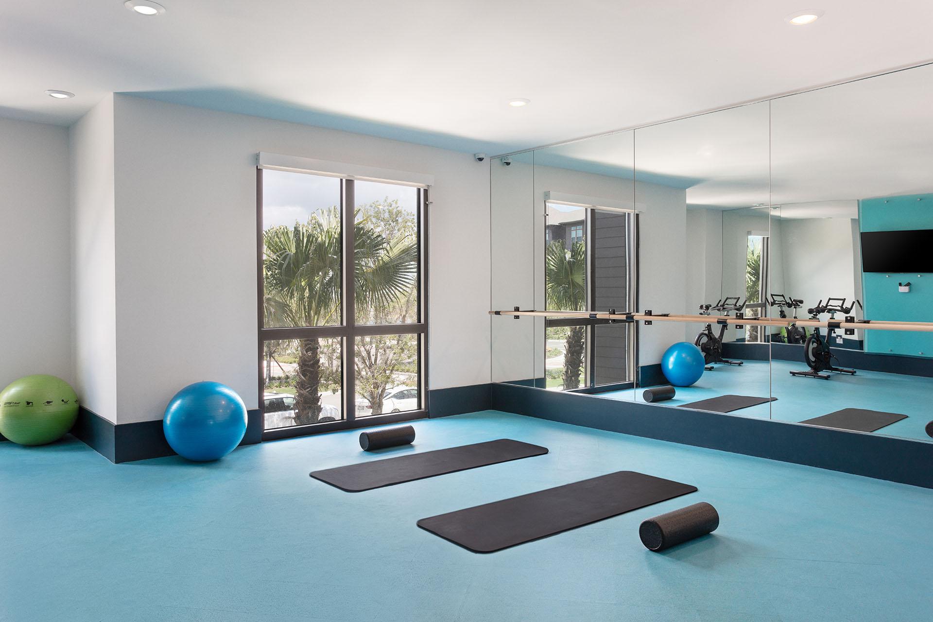 A gym with exercise equipment and a mirror on the wall.