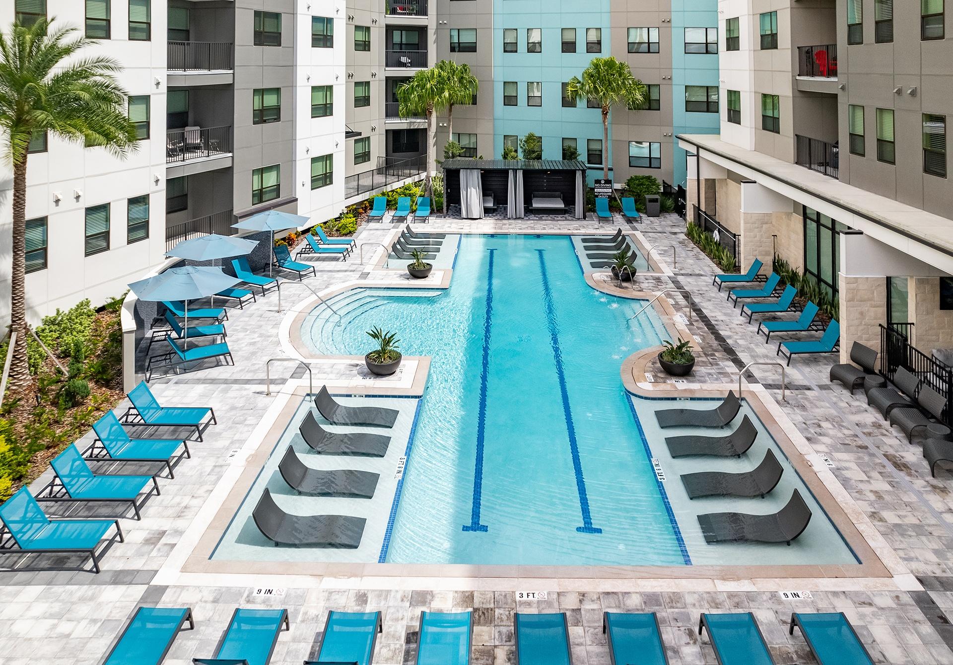 A large swimming pool surrounded by lounge chairs and palm trees.
