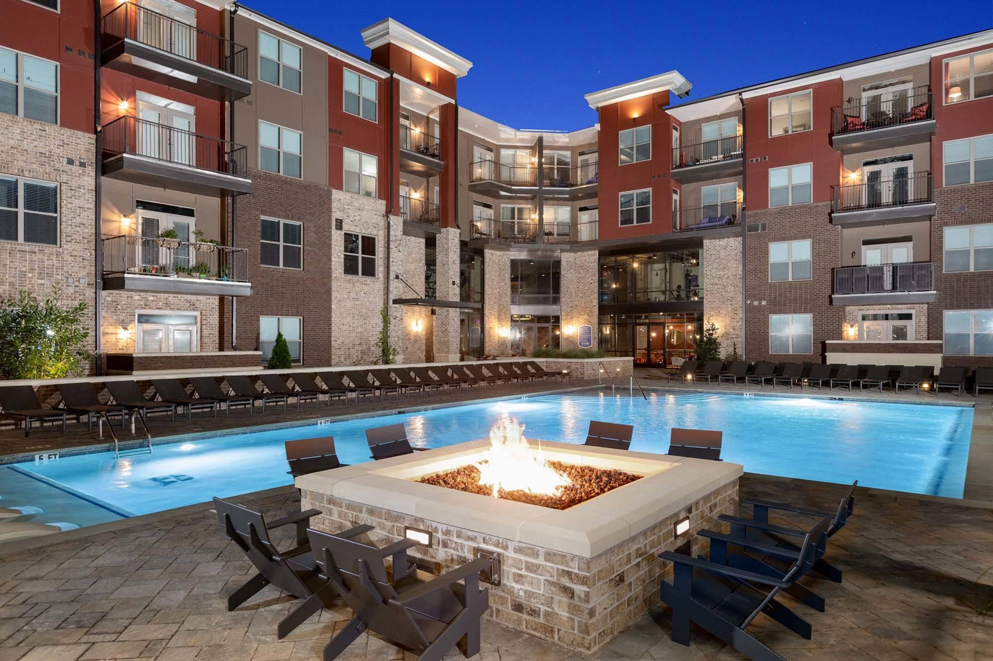 an outdoor pool with a fire pit in front of an apartment building