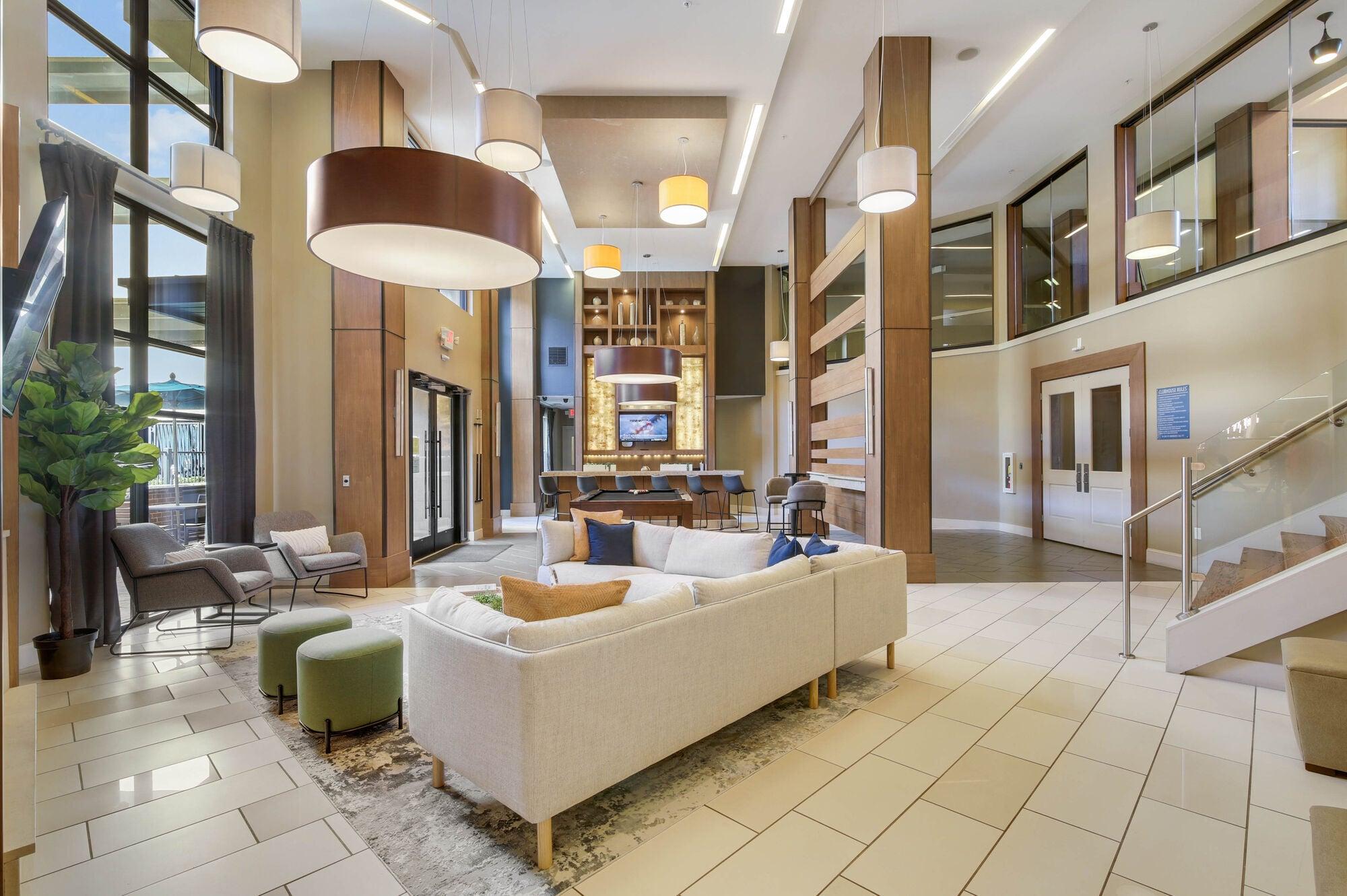 A large white couch is in the middle of a spacious room with a staircase on the right.
