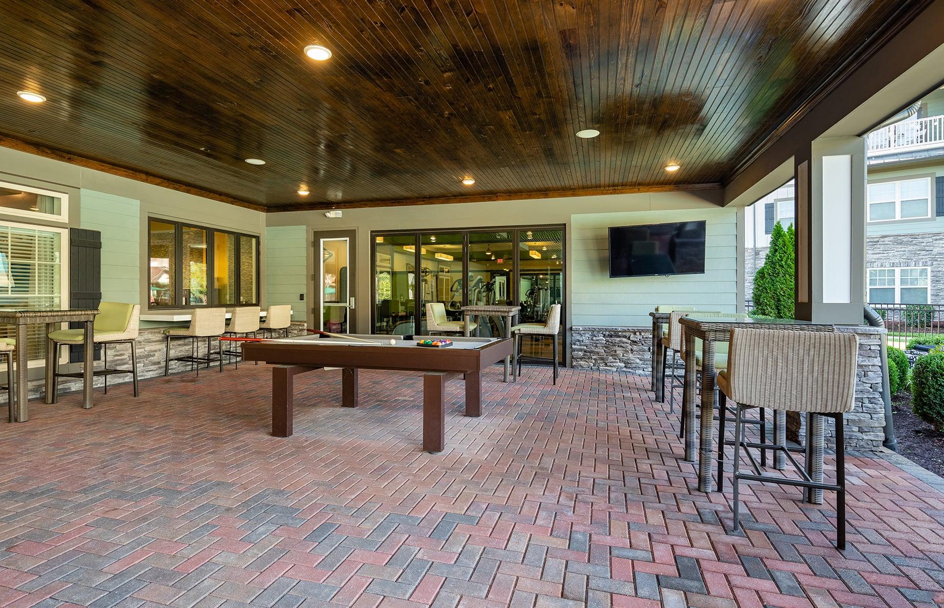 a covered patio with a pool table and tables