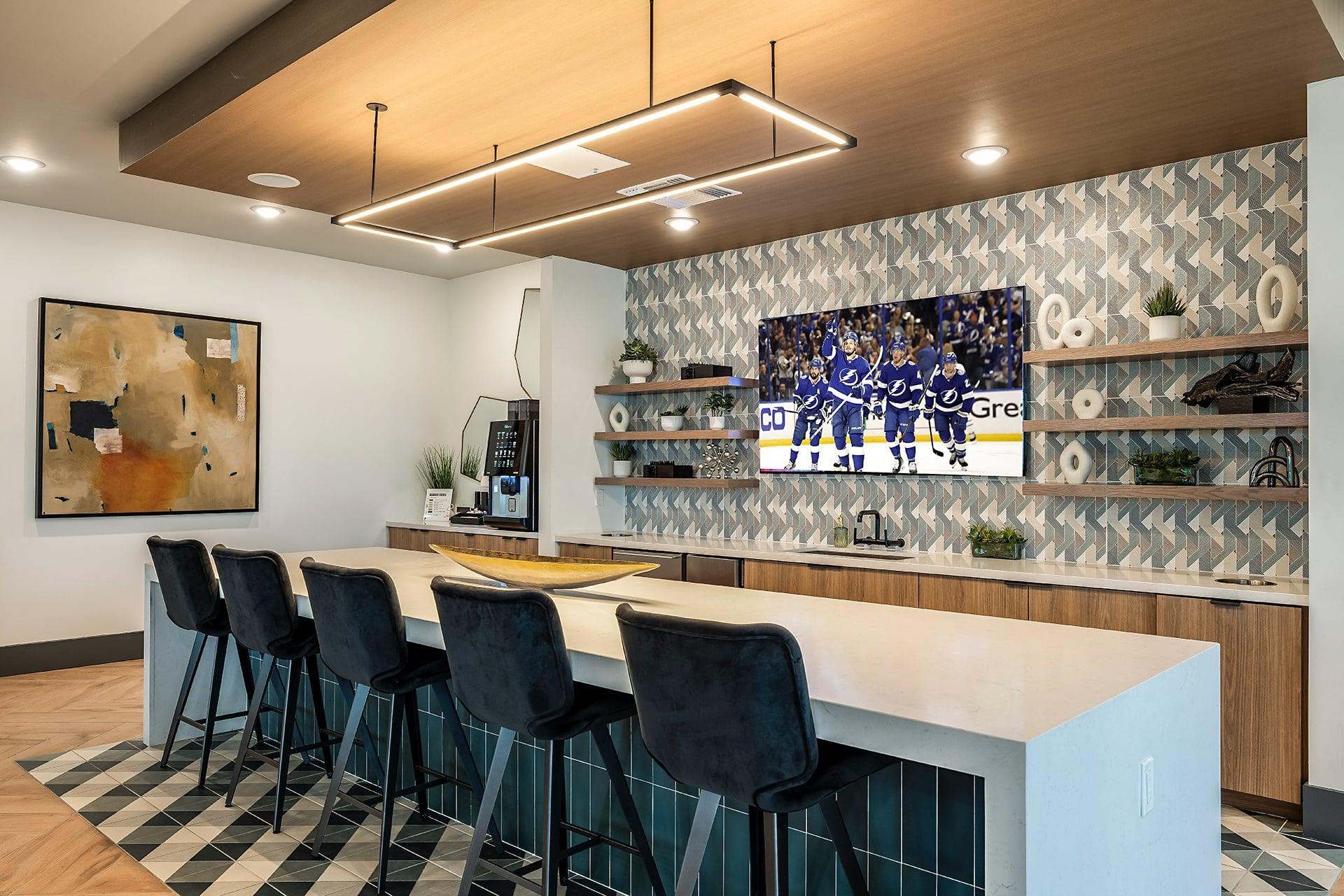 a bar with a white counter and chairs and a tv on the wall