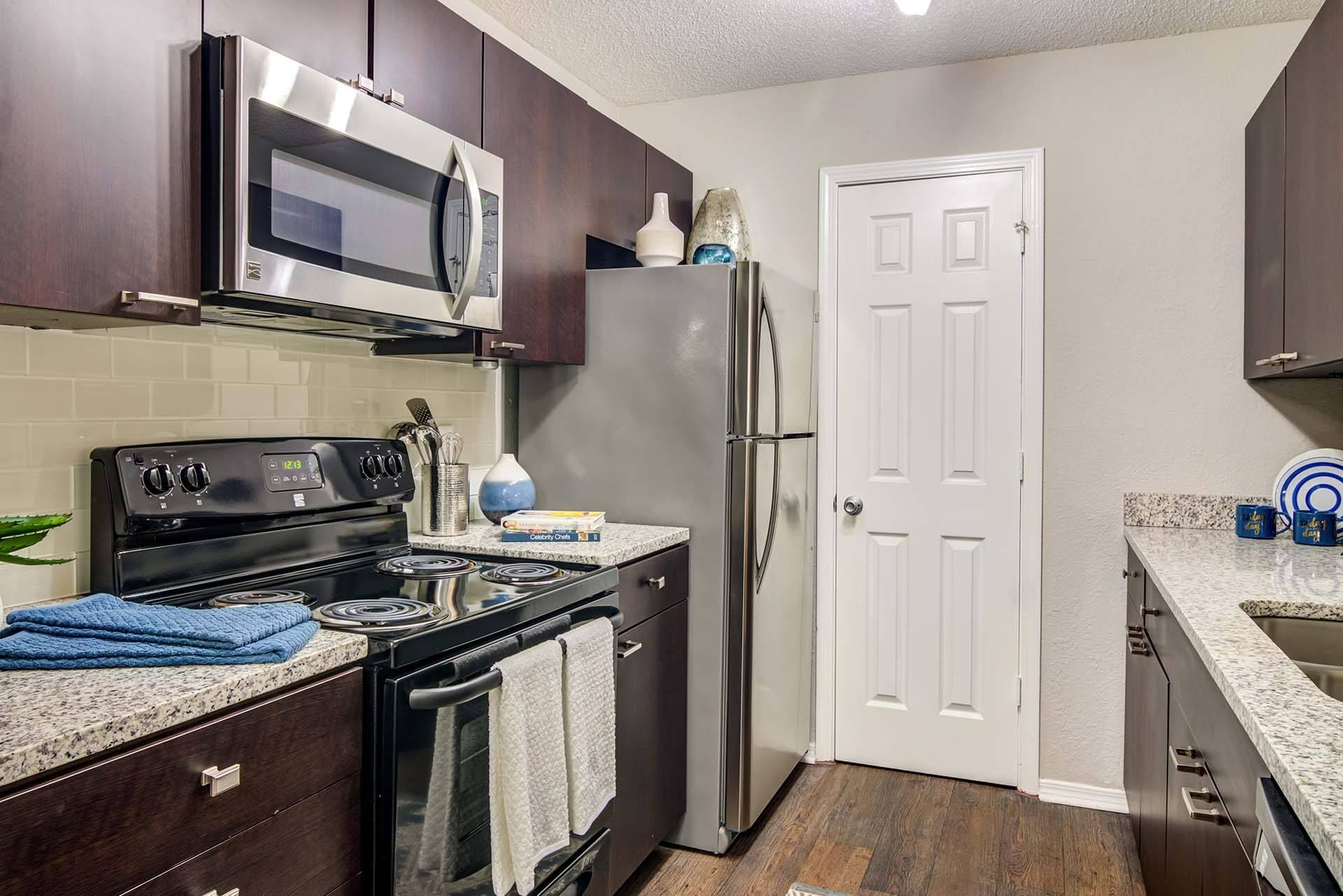 A kitchen with a black stove top oven and a black microwave above it.