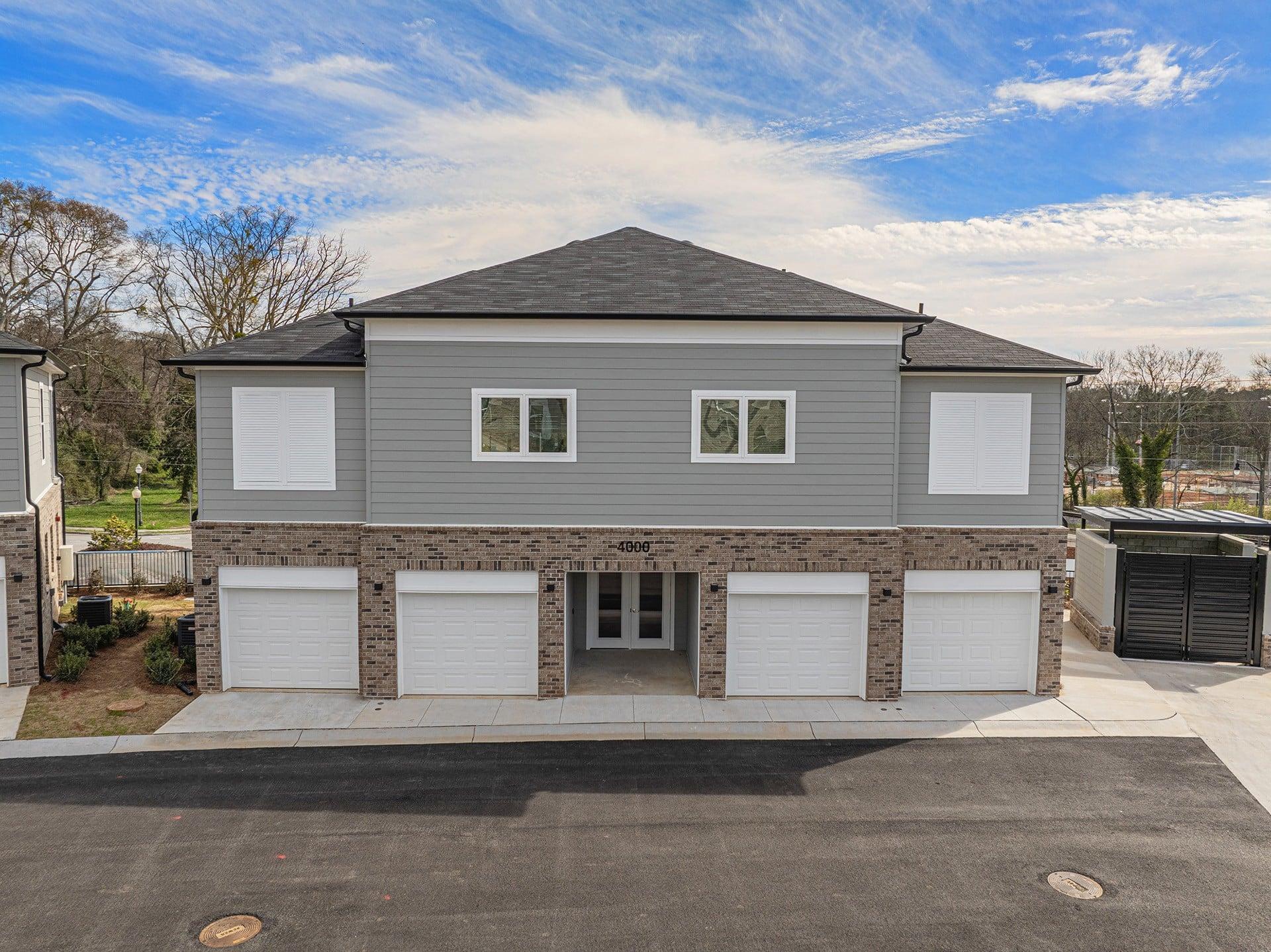 the front of a gray house with white garage doors