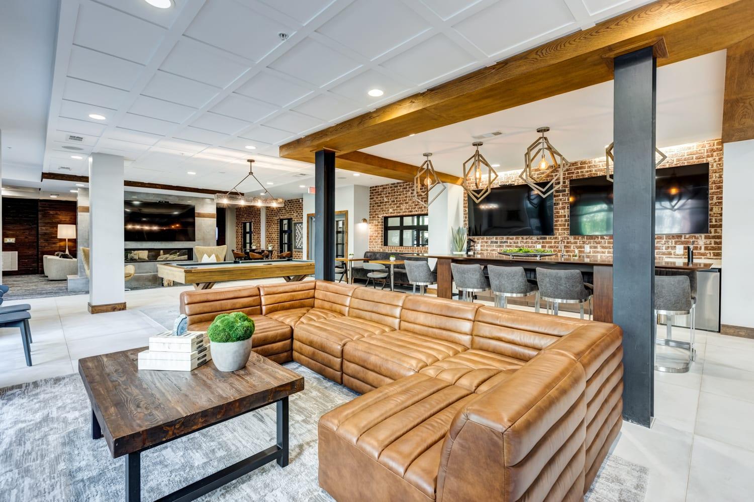 A brown leather couch sits in a modern living room with a wooden coffee table in front of it.