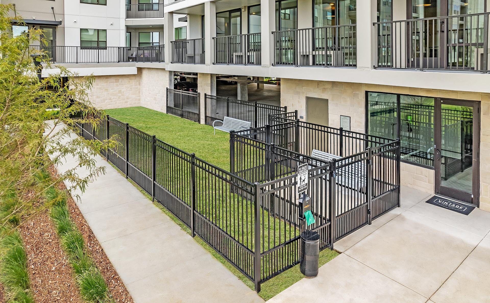 A black metal fence surrounds a green lawn in front of a building.