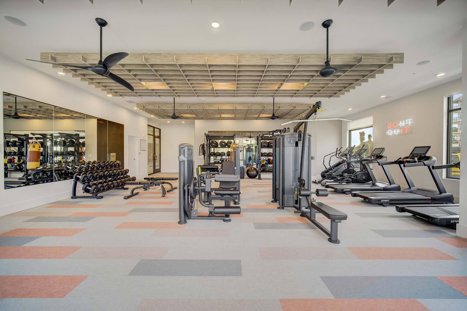 A gym with a variety of equipment including treadmills, weights, and exercise machines.