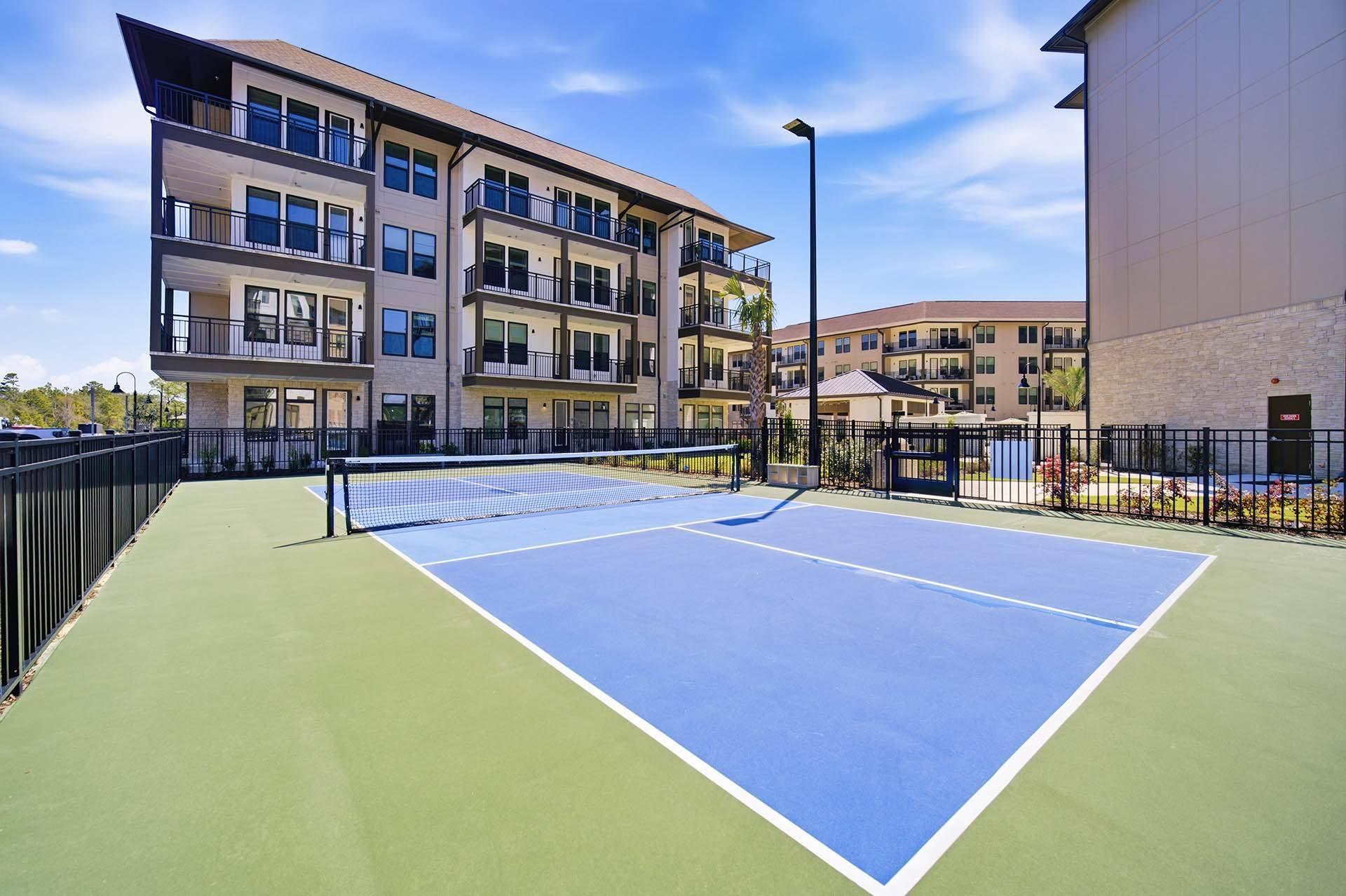 A tennis court is located in front of a building.