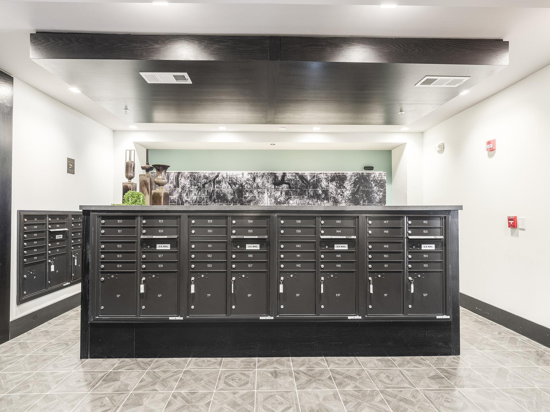 A black mailbox with a green wall in the background.